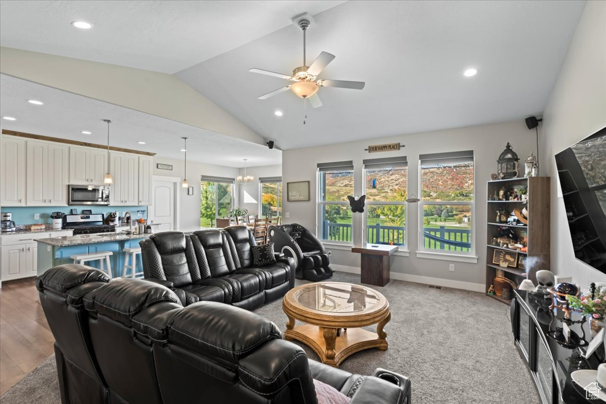 Living room featuring light wood-type flooring, lofted ceiling, and ceiling fan