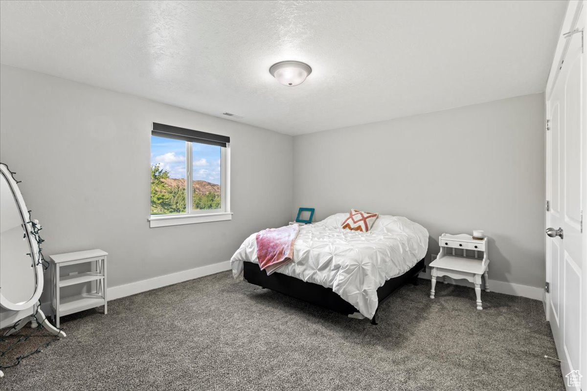 Bedroom with dark colored carpet and a textured ceiling