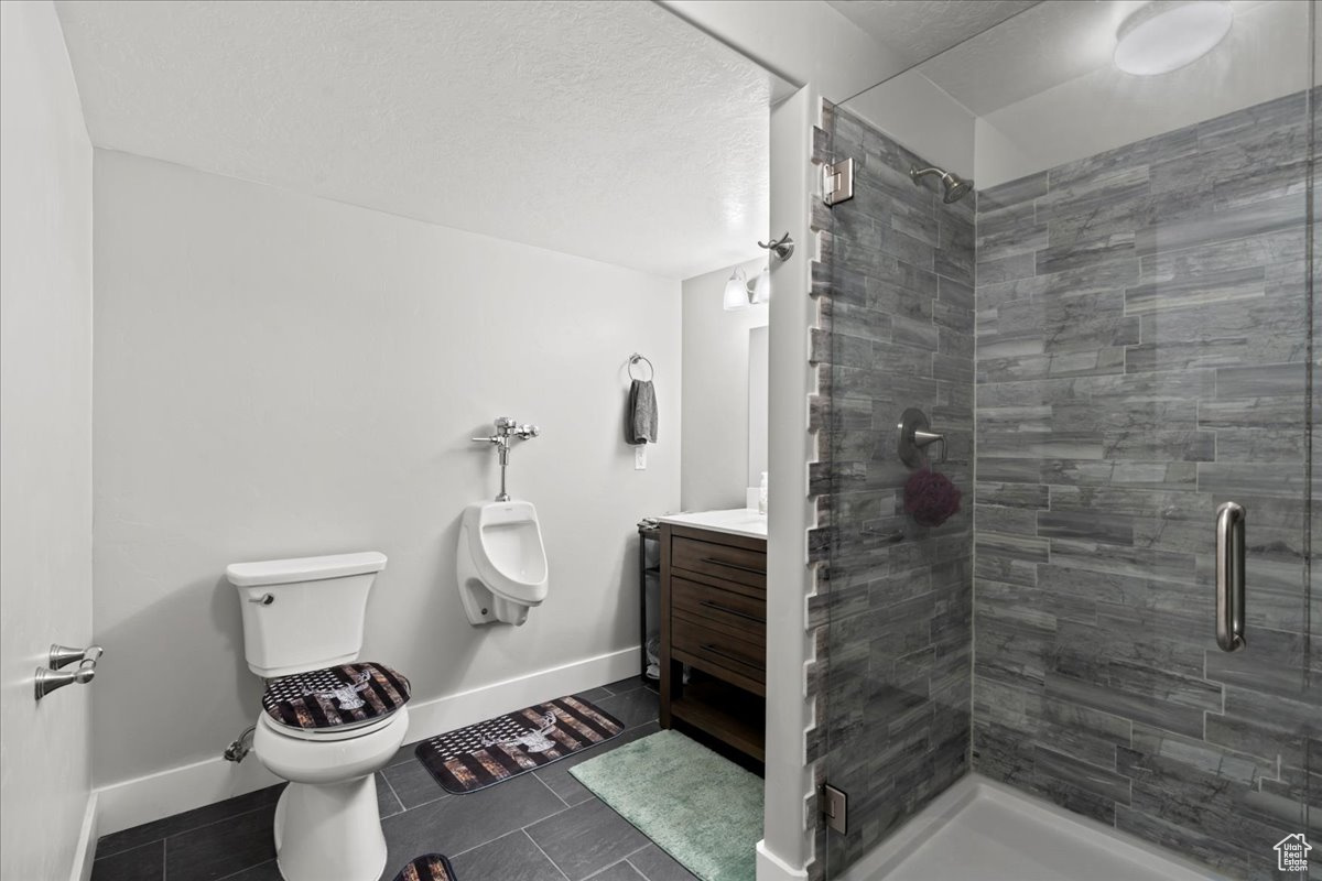 Bathroom featuring vanity, toilet, tile patterned floors, and a shower with door