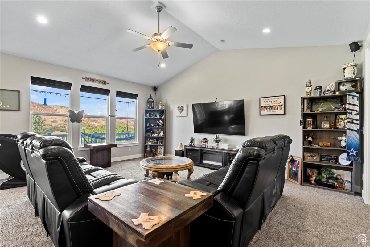 Carpeted living room with ceiling fan and vaulted ceiling