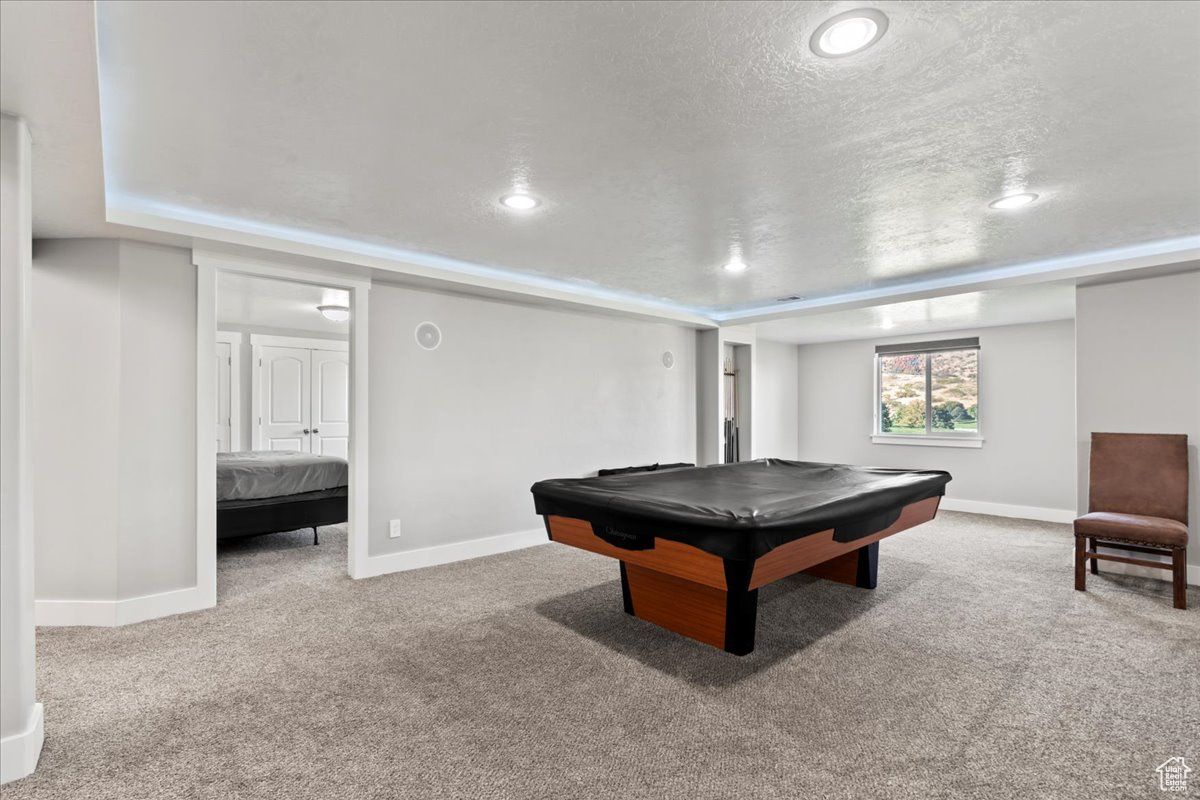 Recreation room featuring light carpet, a textured ceiling, and billiards