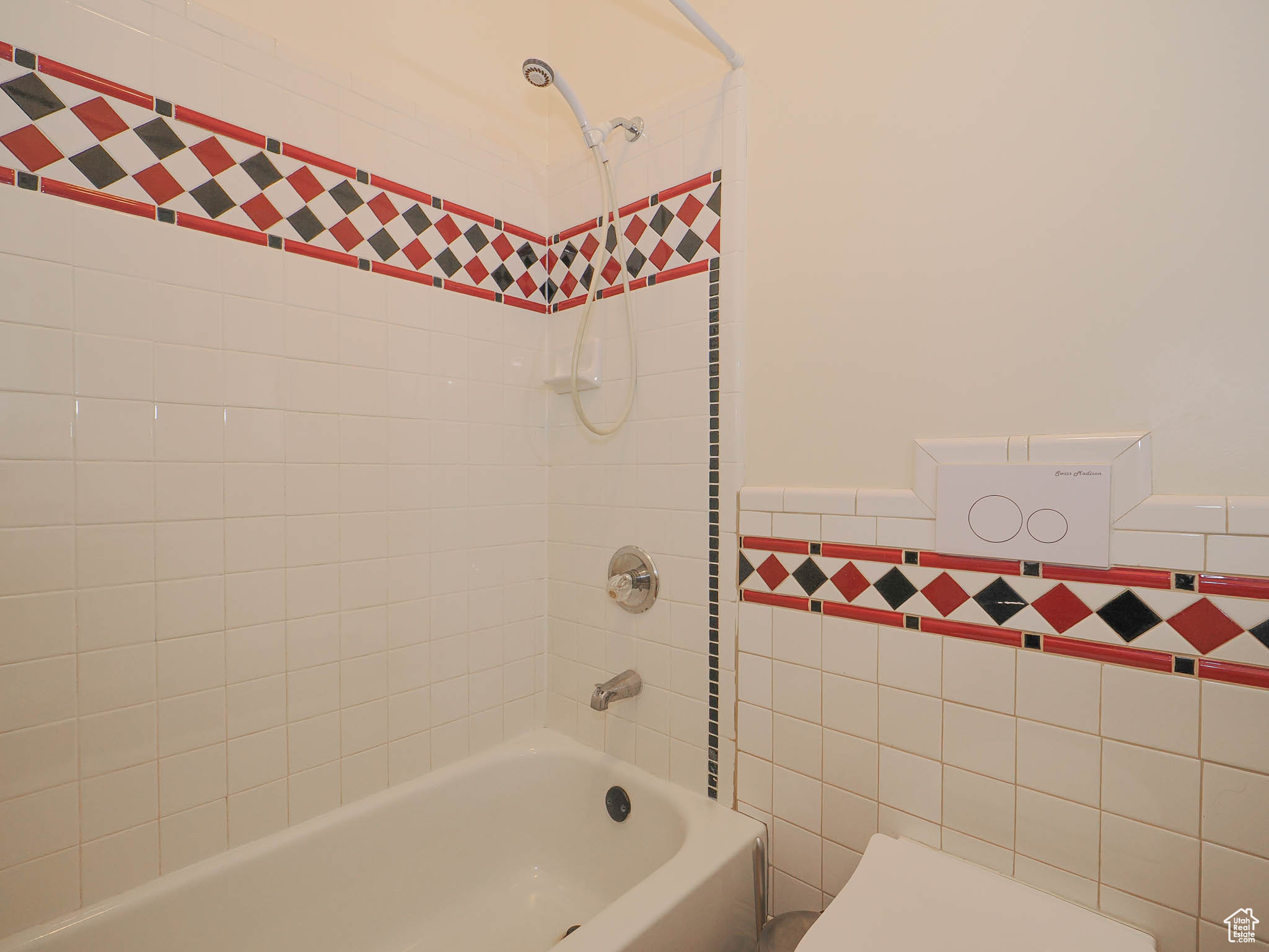 Bathroom with tiled shower / bath combo, tile walls, and toilet