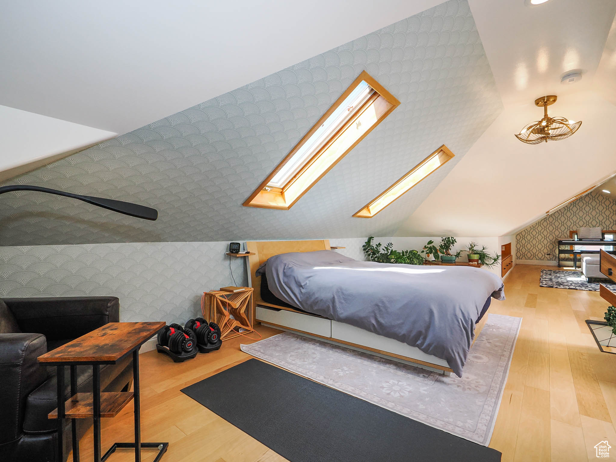 Bedroom featuring vaulted ceiling with skylight and light hardwood / wood-style floors