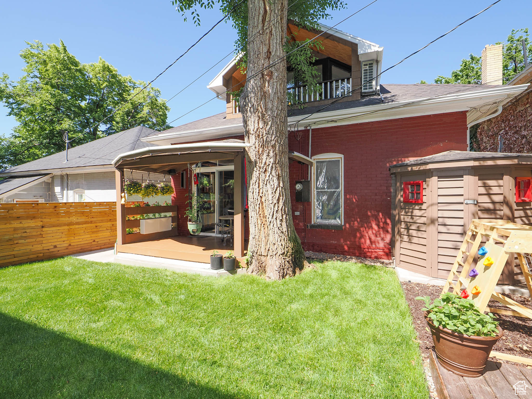 Rear view of house featuring a balcony, a patio area, and a lawn