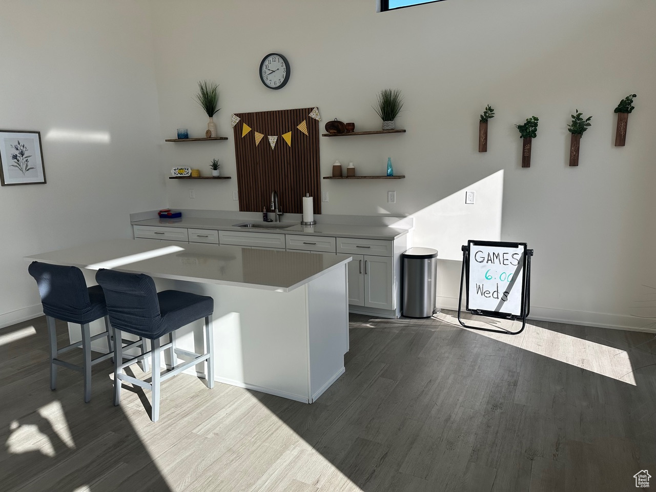 Interior space featuring white cabinetry, a breakfast bar area, dark hardwood / wood-style flooring, a center island, and sink