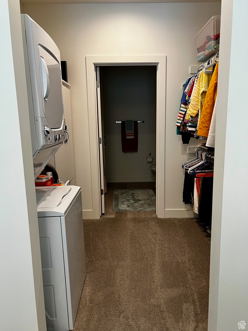 Laundry room with stacked washer / dryer and dark carpet