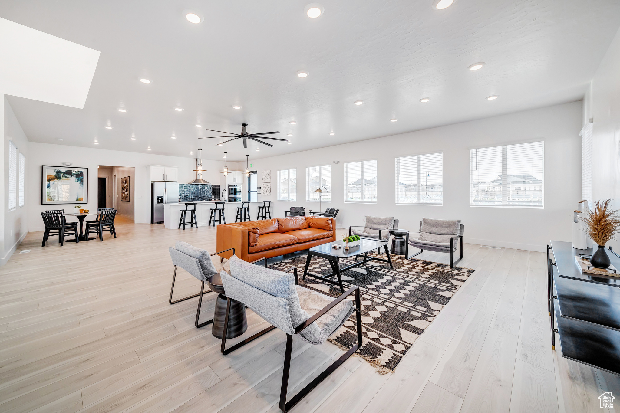 Living room with ceiling fan, a skylight, and light hardwood / wood-style flooring