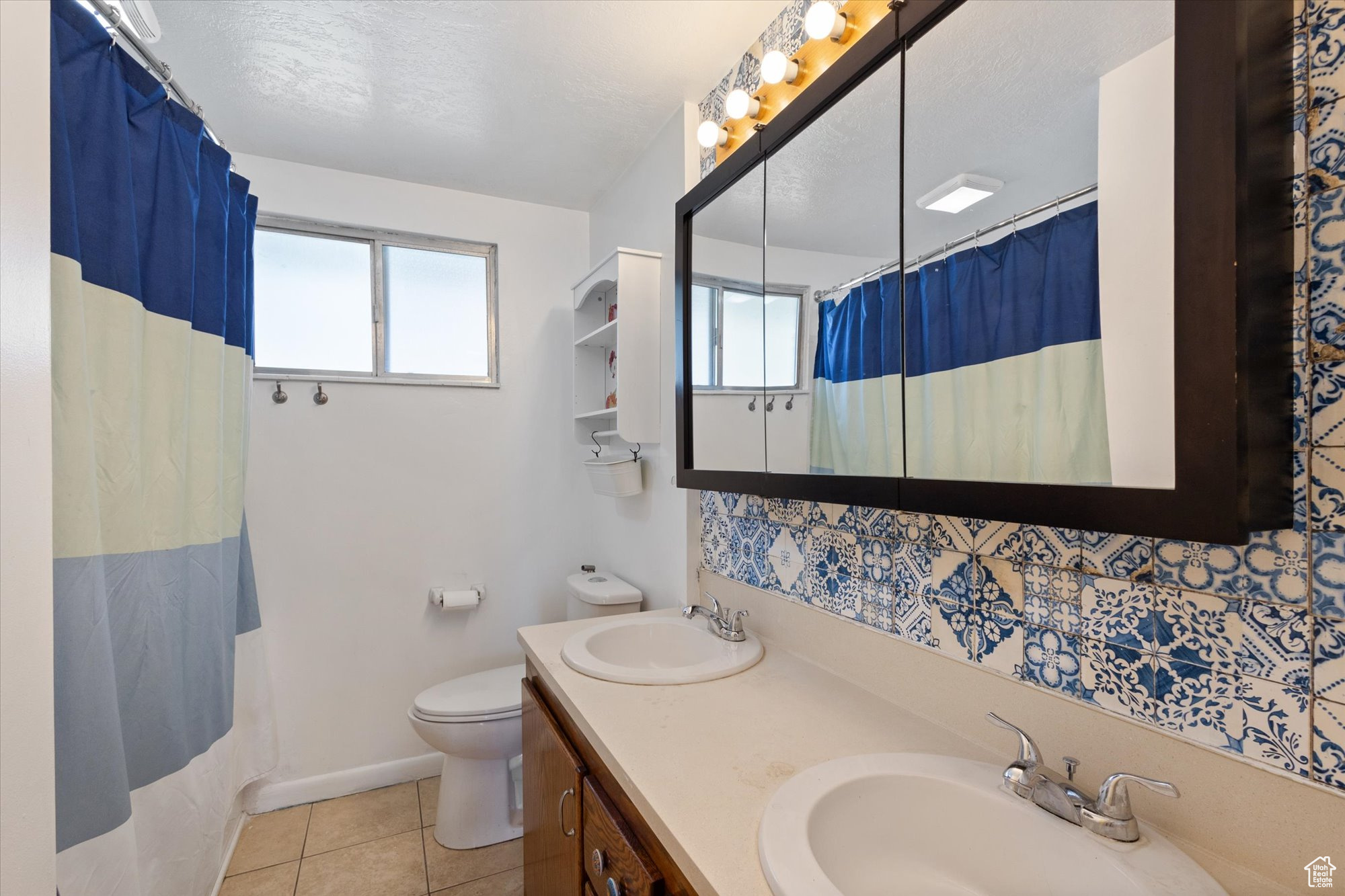 Bathroom with tile patterned flooring, a textured ceiling, toilet, vanity, and curtained shower