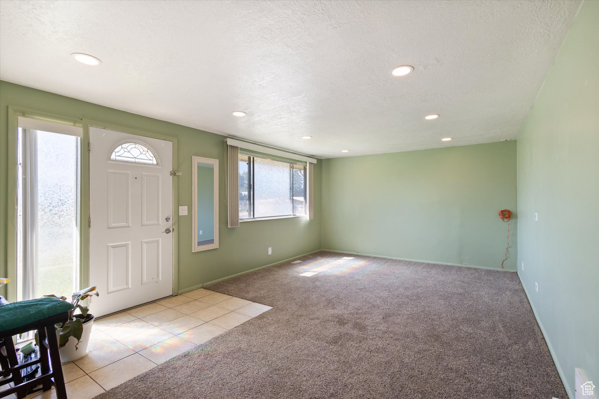 Carpeted foyer entrance with a textured ceiling