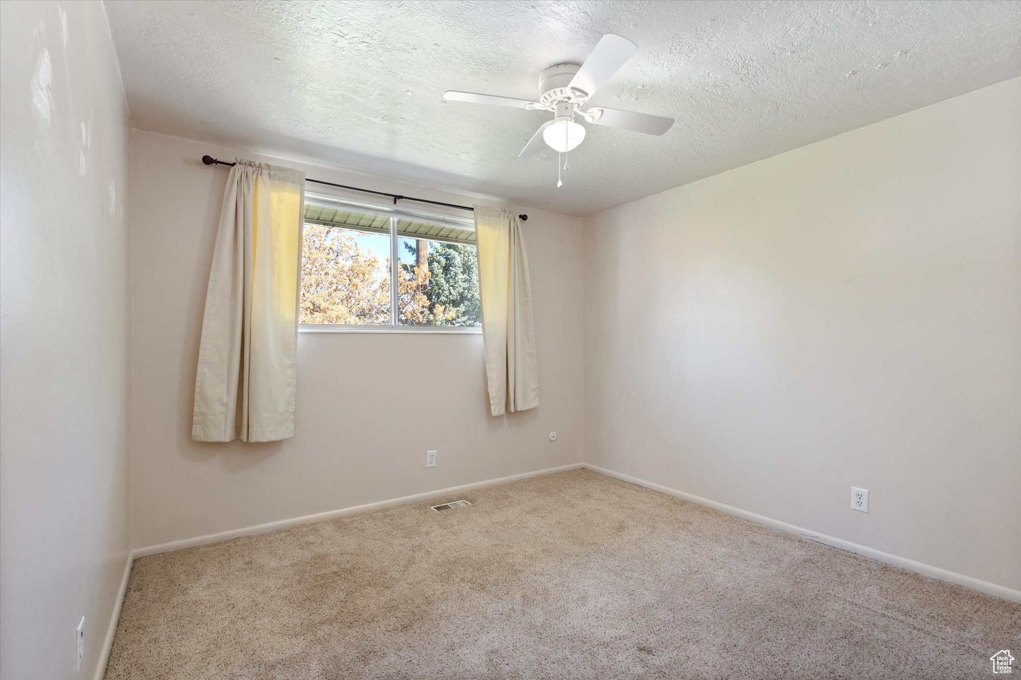 Carpeted spare room featuring a textured ceiling and ceiling fan