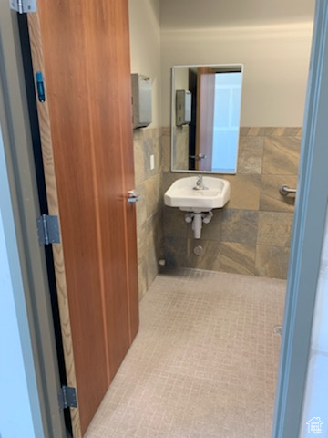 Bathroom featuring tile walls, tile patterned floors, and sink