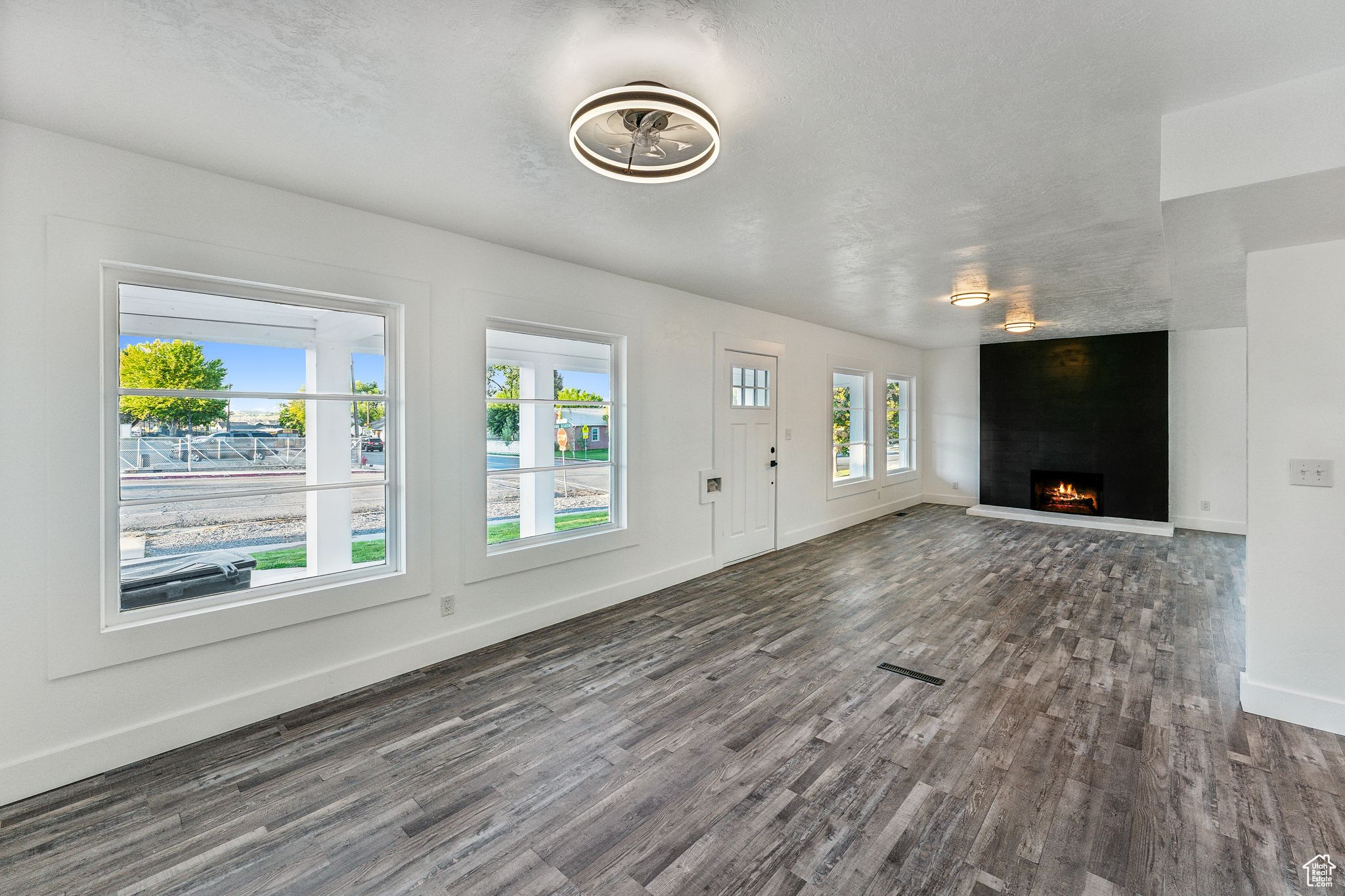 Unfurnished living room featuring a textured ceiling, a fireplace, and dark wood-type flooring