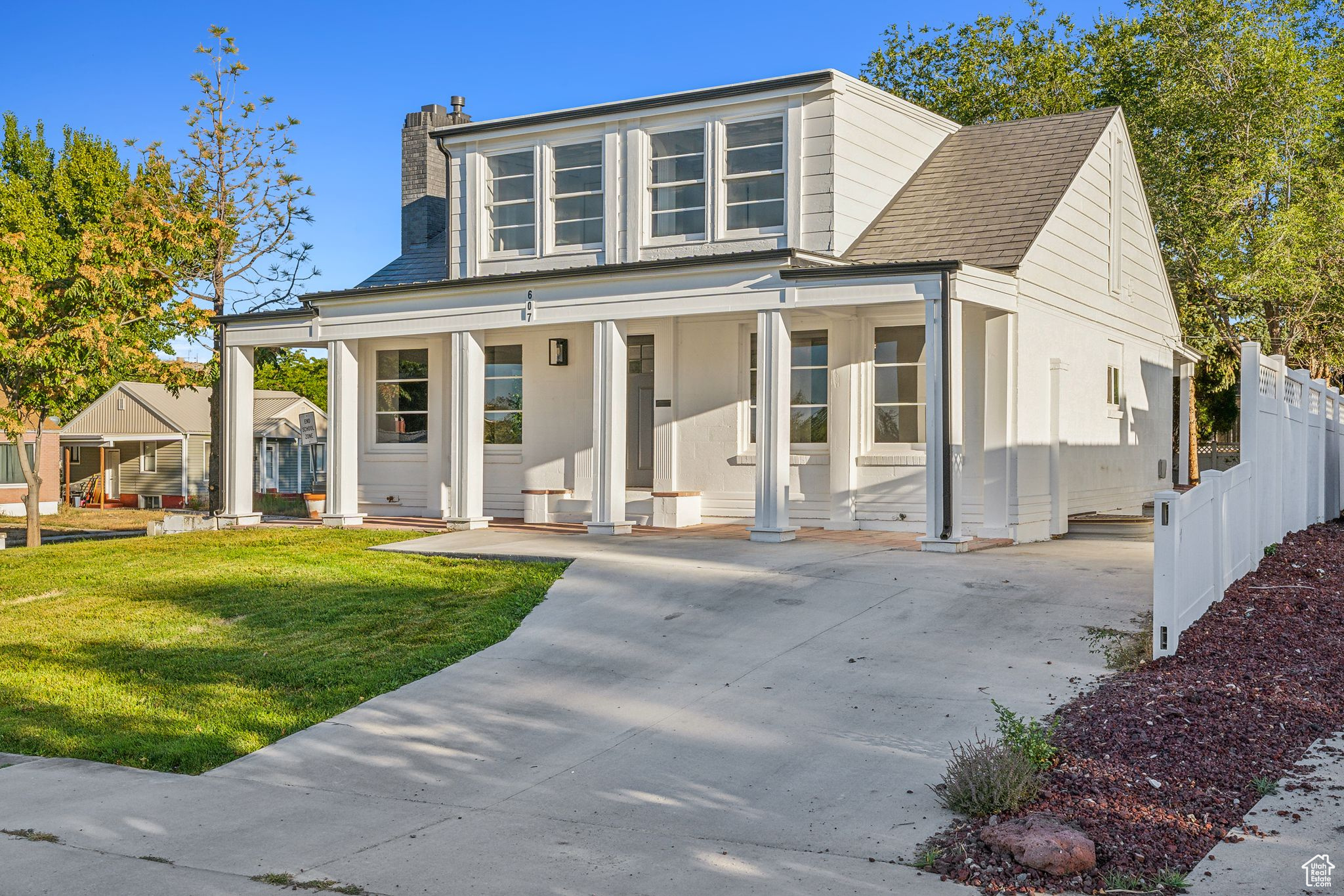 View of front facade with a front yard, covered porch, and a carport