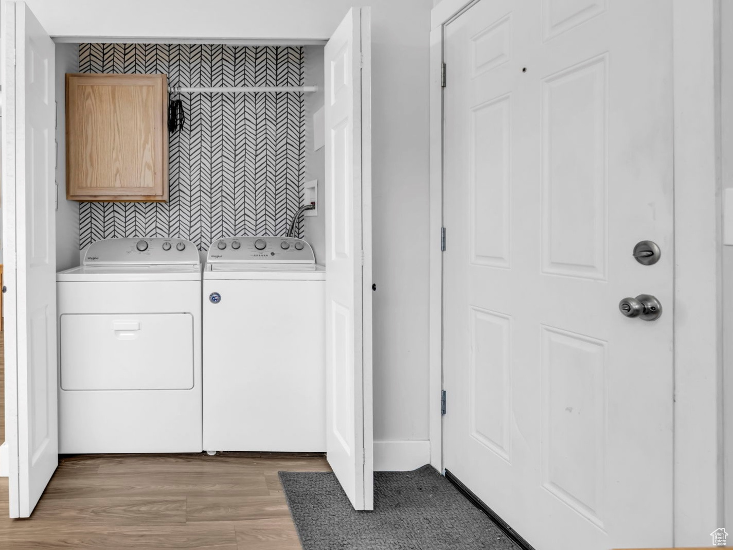 Laundry room with washer and clothes dryer, cabinets, and wood-type flooring