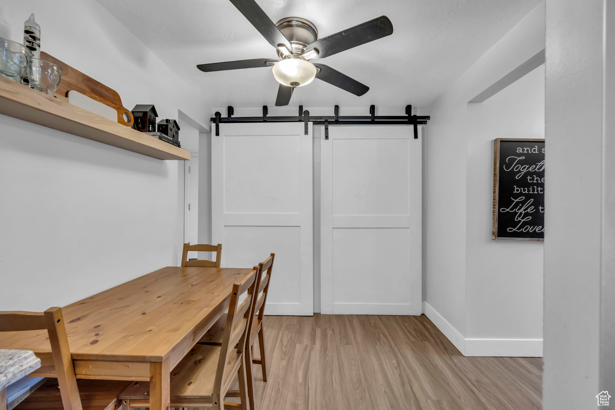 Dining area featuring a barn door, light hardwood / wood-style floors, and ceiling fan