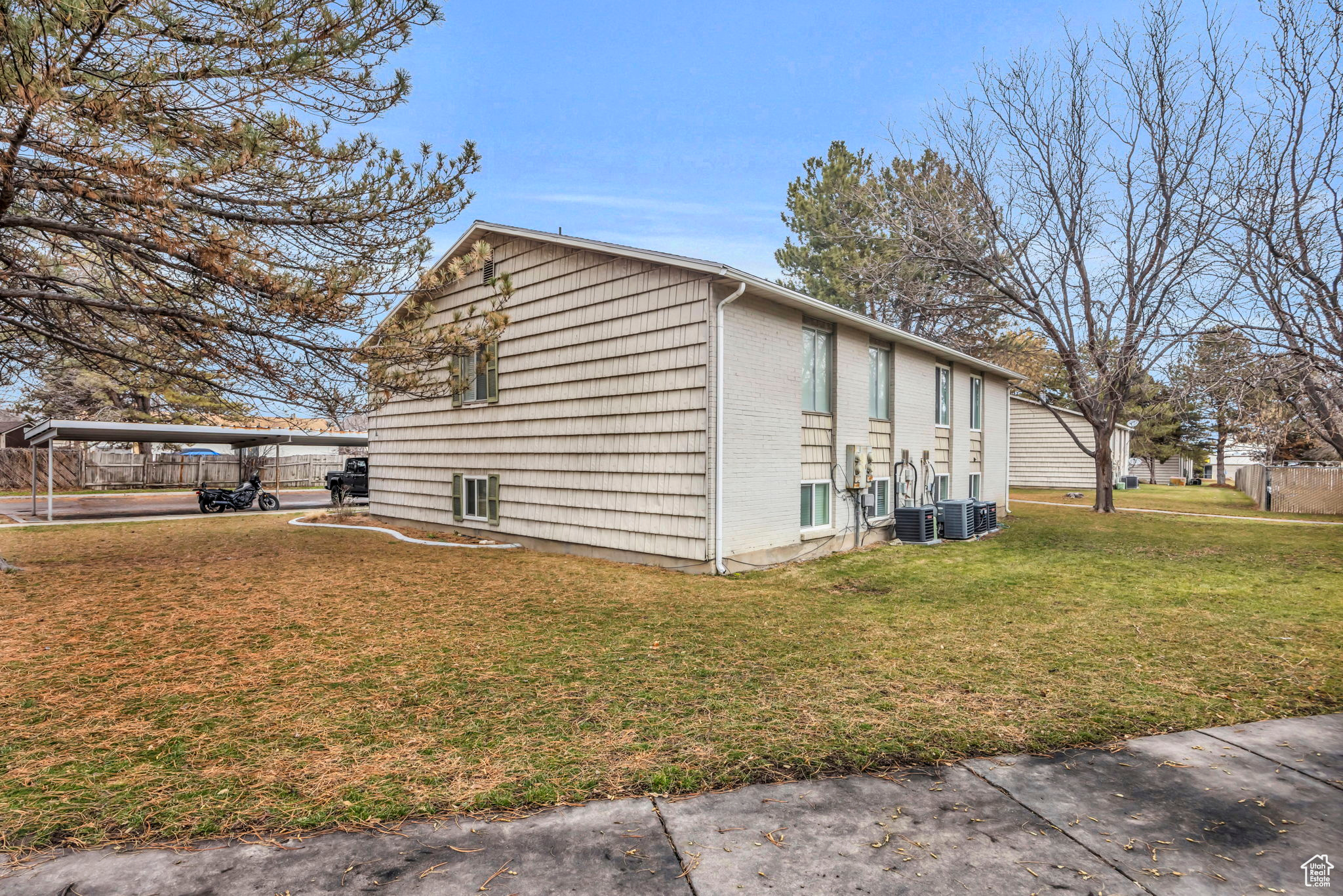 View of side of home featuring central AC, a yard, and a carport