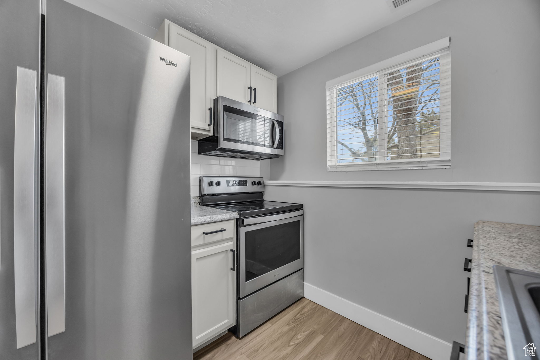 Kitchen with white cabinets, sink, light wood-type flooring, and stainless steel appliances