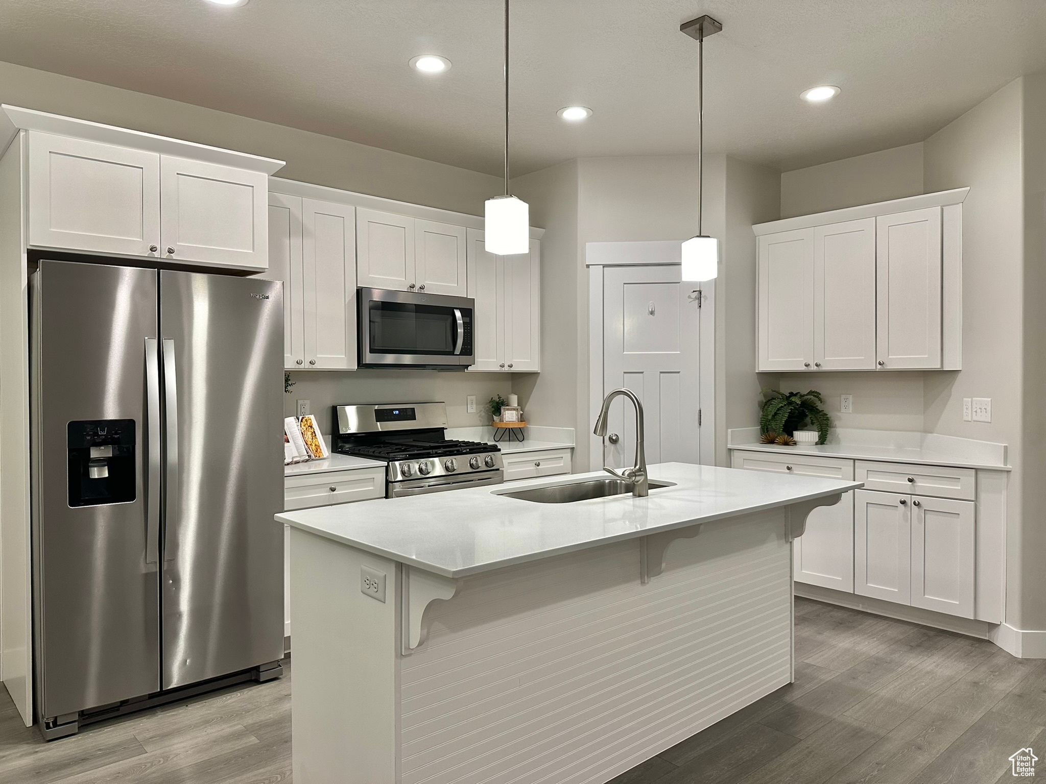 Kitchen featuring pendant lighting, sink, an island with sink, white cabinets, and appliances with stainless steel finishes