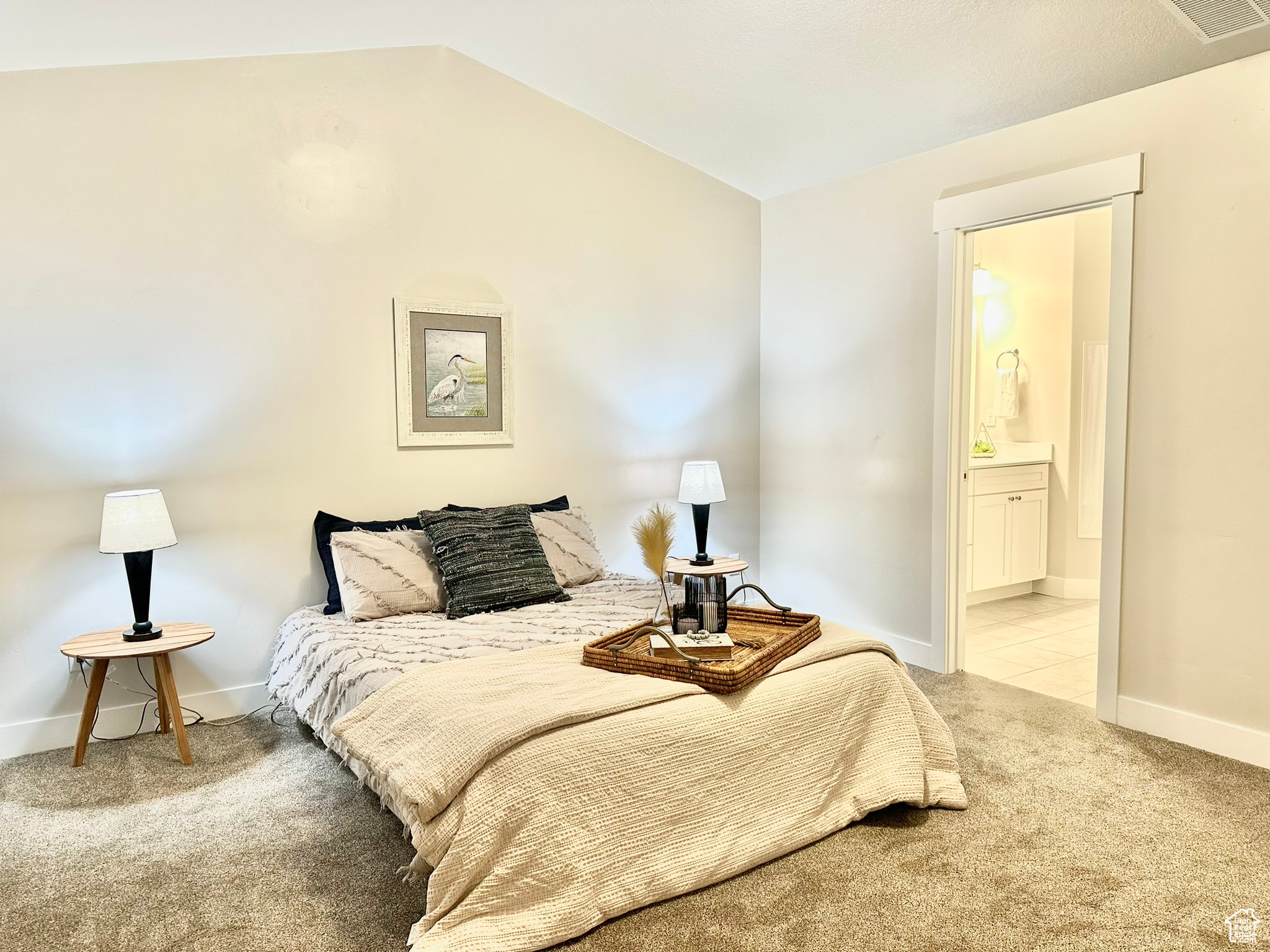 Carpeted bedroom featuring vaulted ceiling and ensuite bath