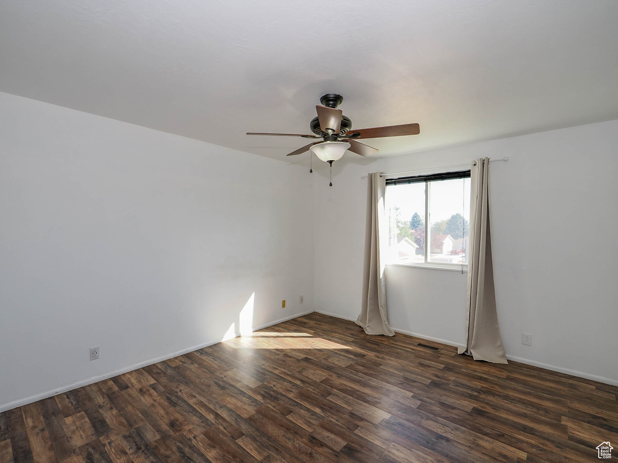 Empty room featuring dark hardwood / wood-style flooring and ceiling fan