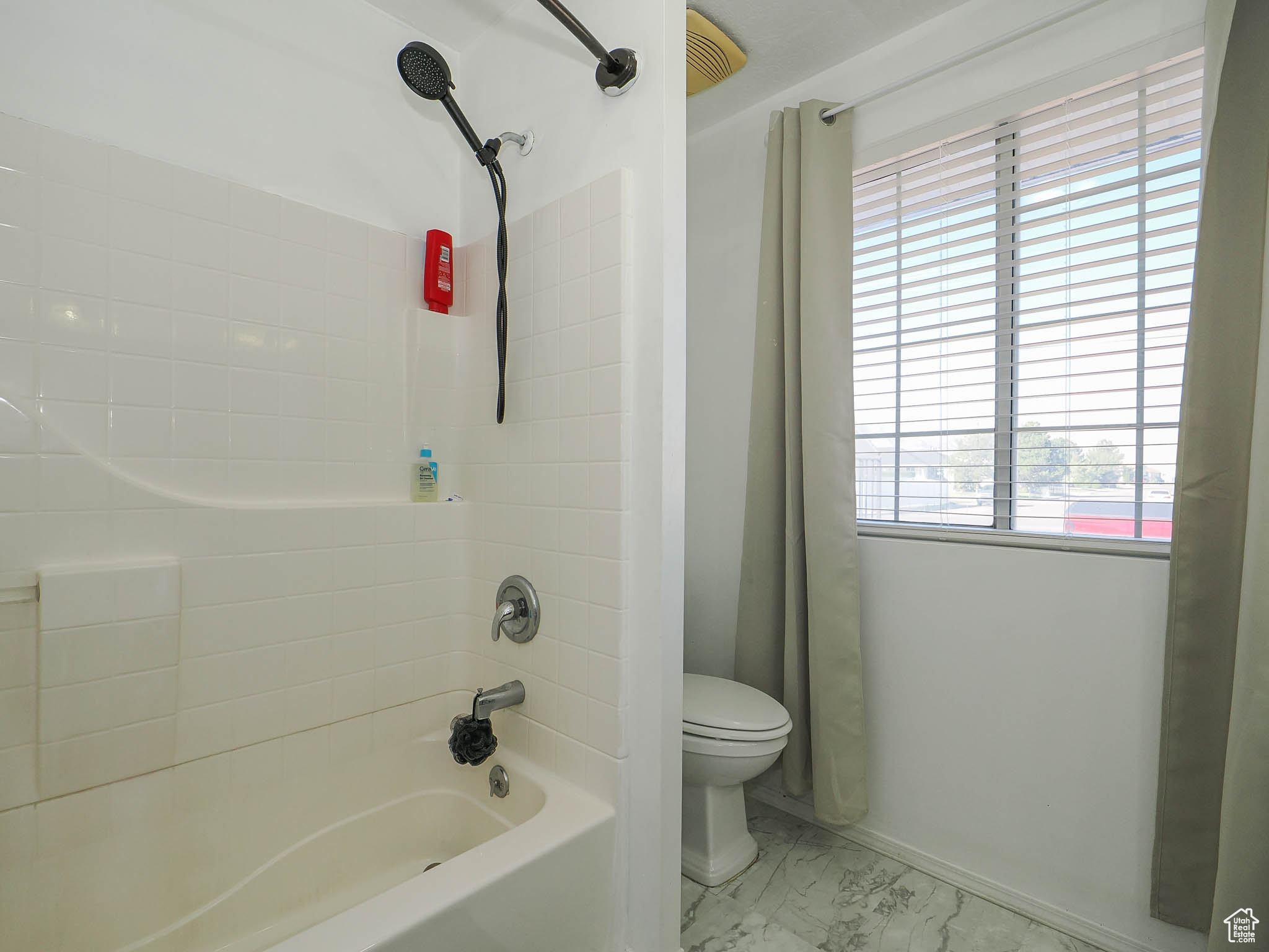 Bathroom with a wealth of natural light, shower / tub combo with curtain, and toilet