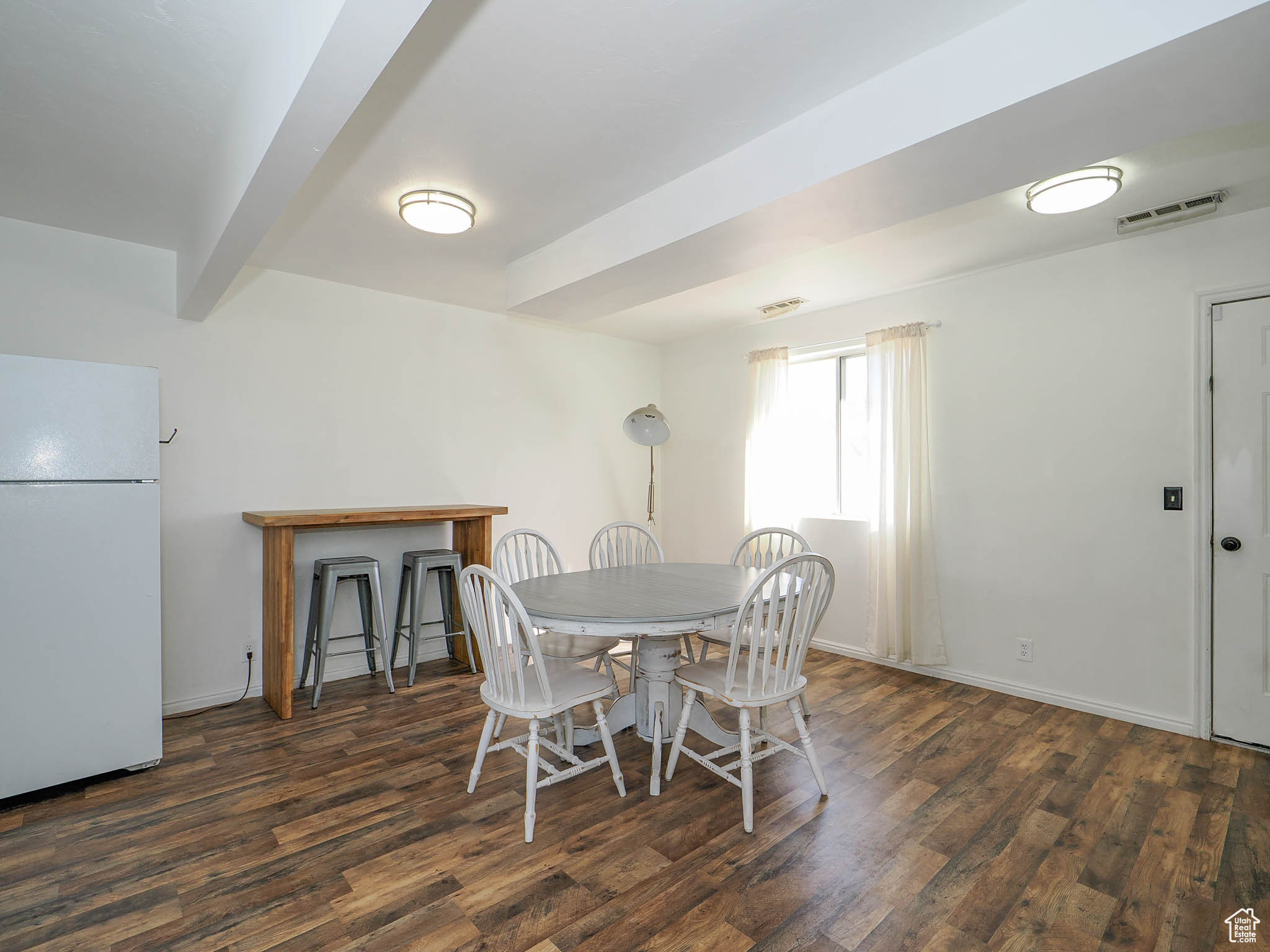 Dining space with dark hardwood / wood-style floors and beam ceiling