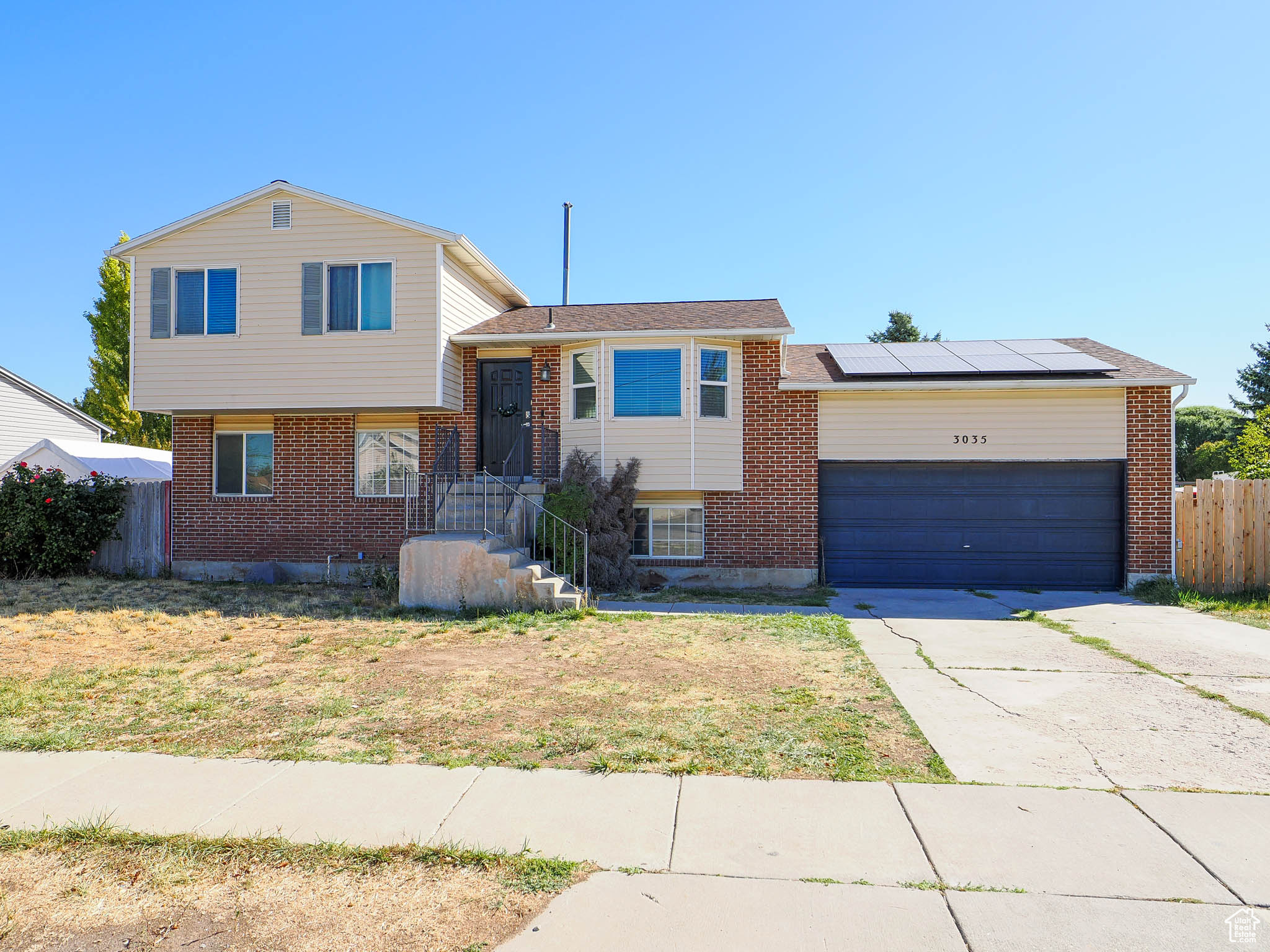 Tri-level home with a front yard, solar panels, and a garage