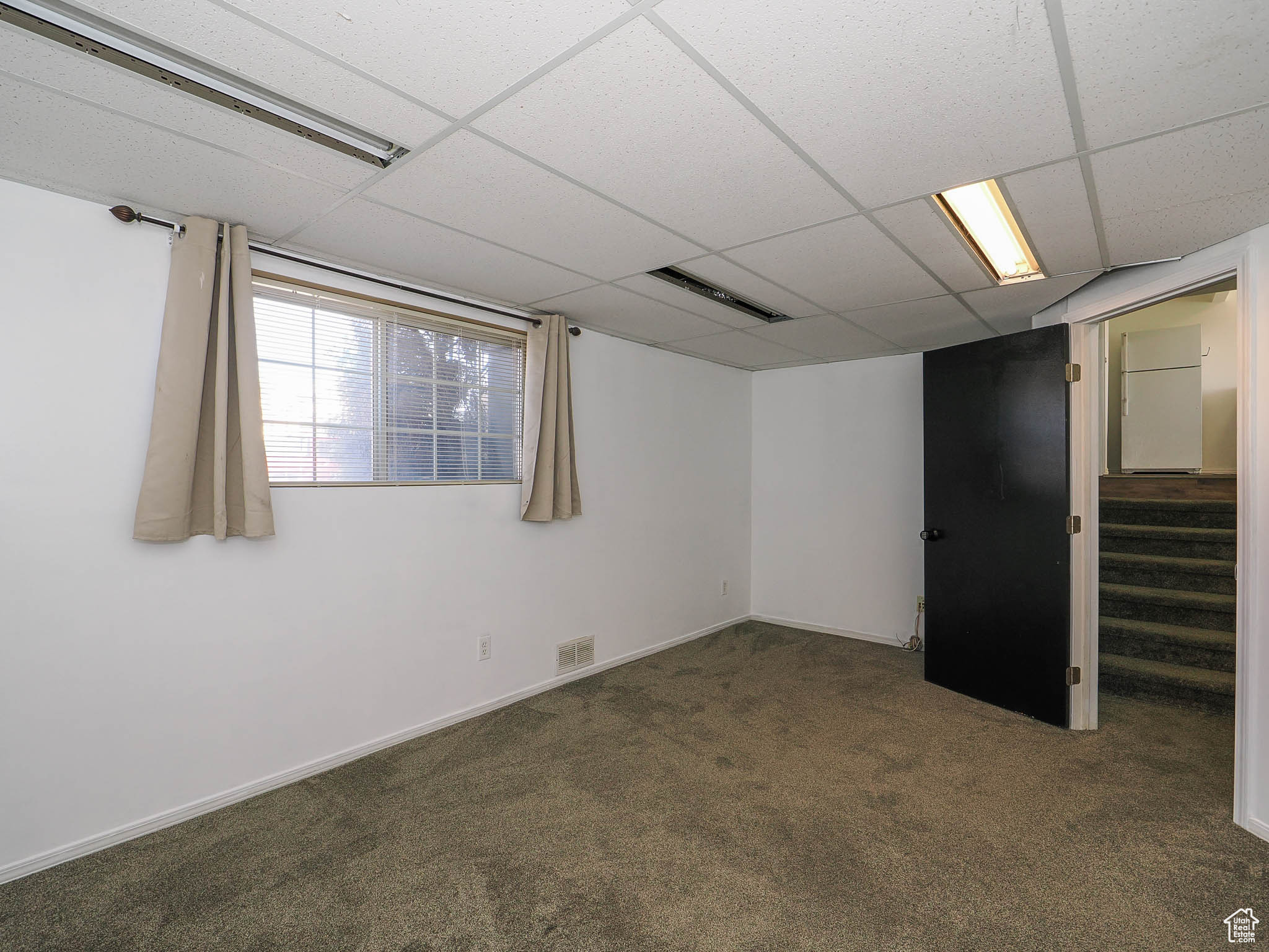 Basement with a paneled ceiling and dark carpet