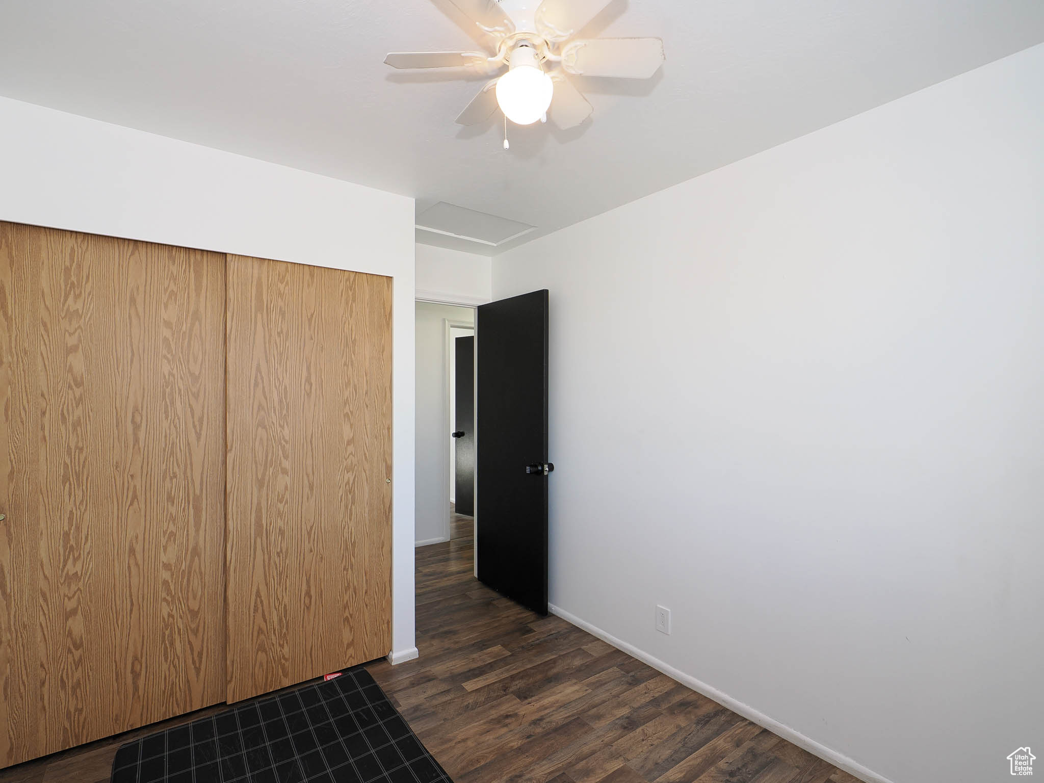 Unfurnished bedroom with ceiling fan, a closet, and dark wood-type flooring