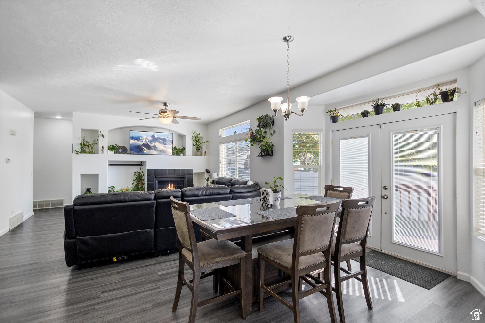 Dining space featuring ceiling fan with notable chandelier, a fireplace, dark hardwood / wood-style floors, and a wealth of natural light