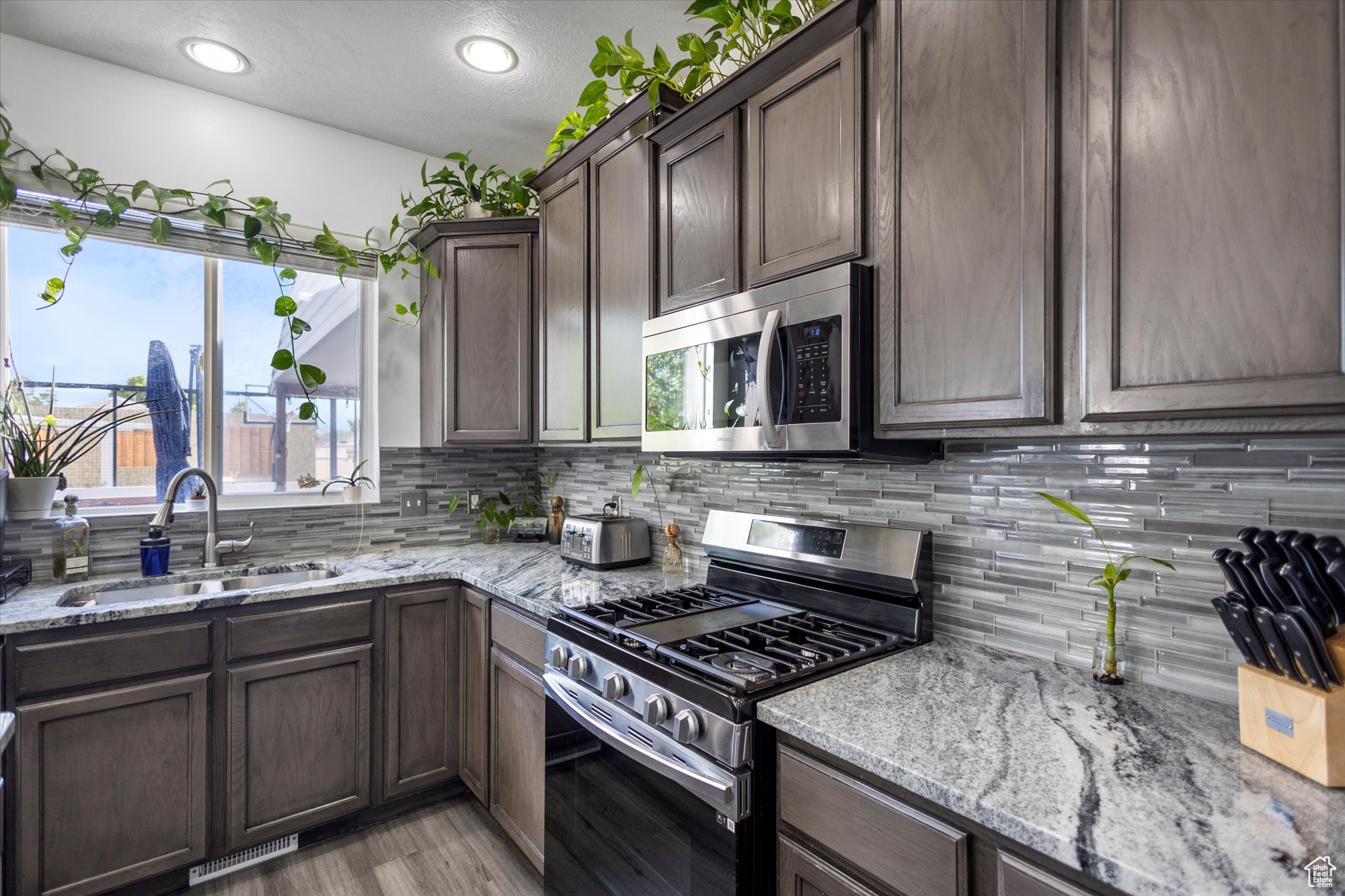 Kitchen with light stone countertops, dark brown cabinets, appliances with stainless steel finishes, and sink