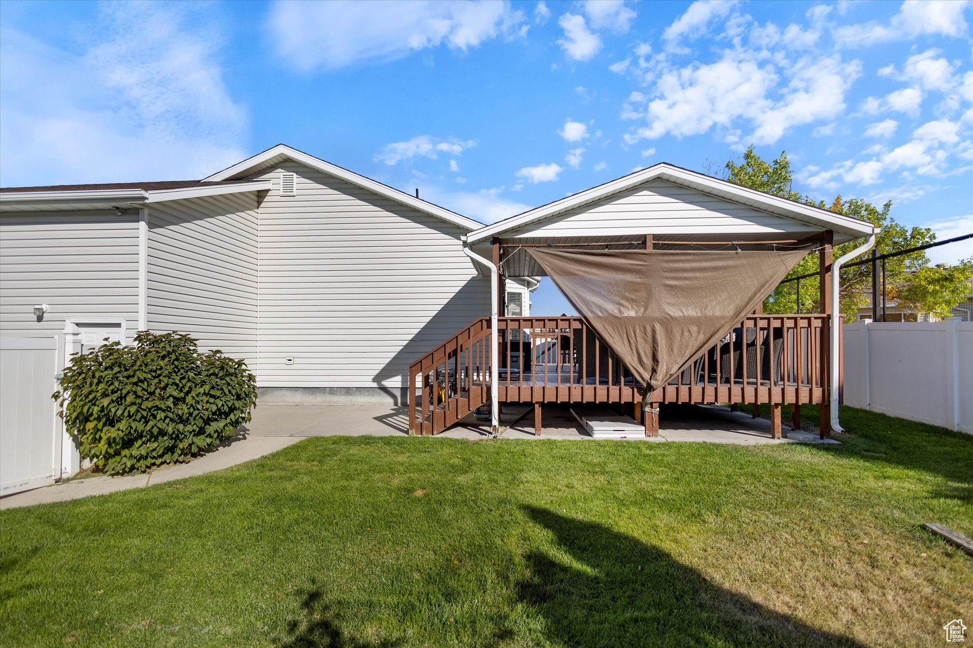 Rear view of house featuring a lawn, a patio, and a wooden deck