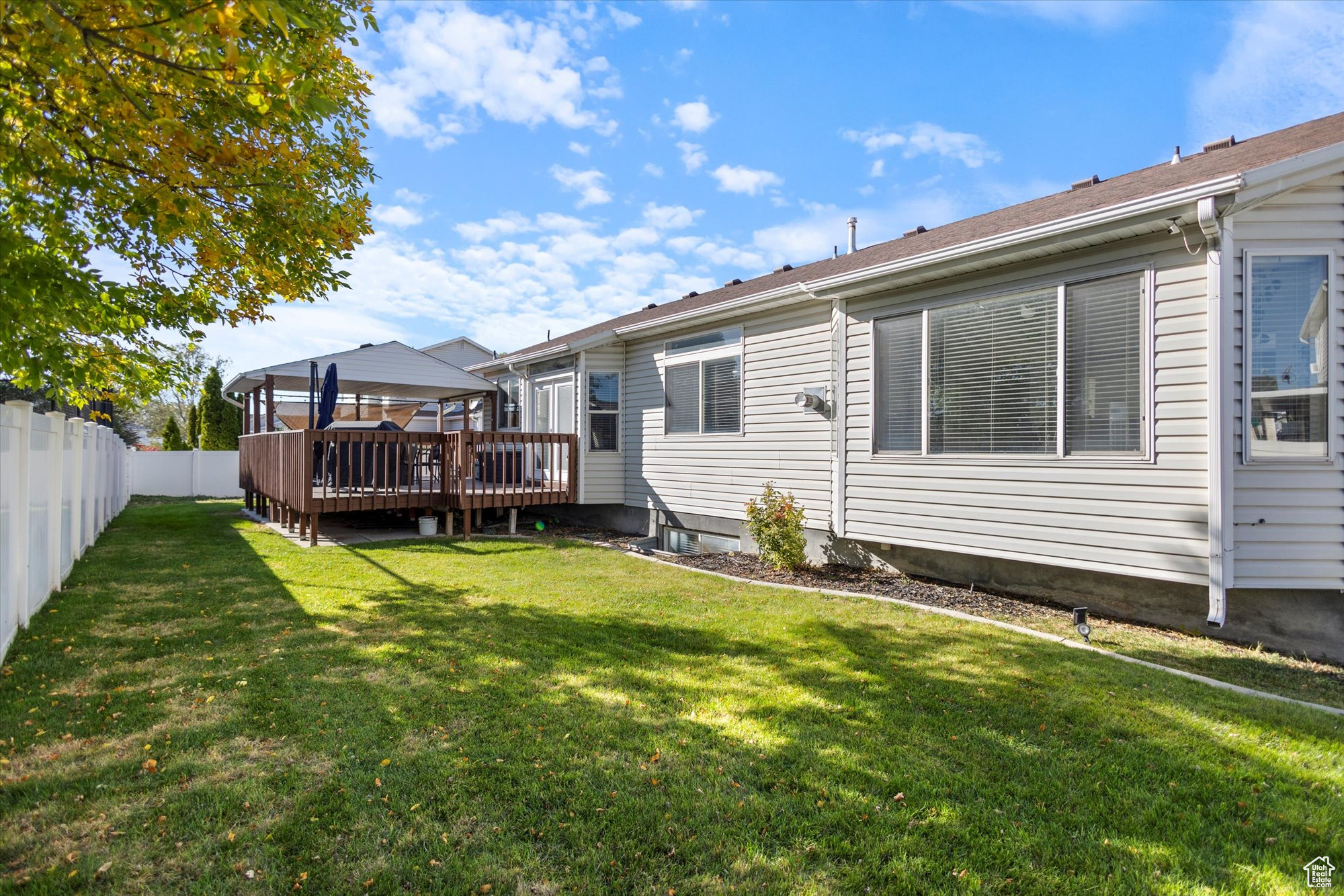 Rear view of property featuring a wooden deck and a lawn