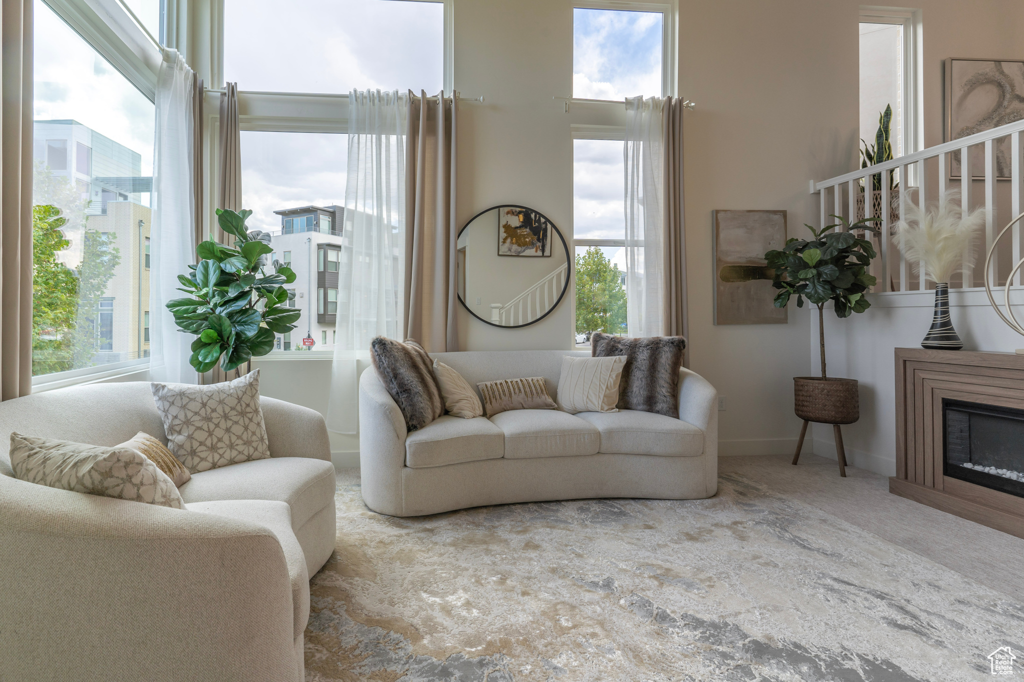 This generously sized living room offers a grand entry with a soaring ceiling and a staircase to the open concept dining and kitchen area.