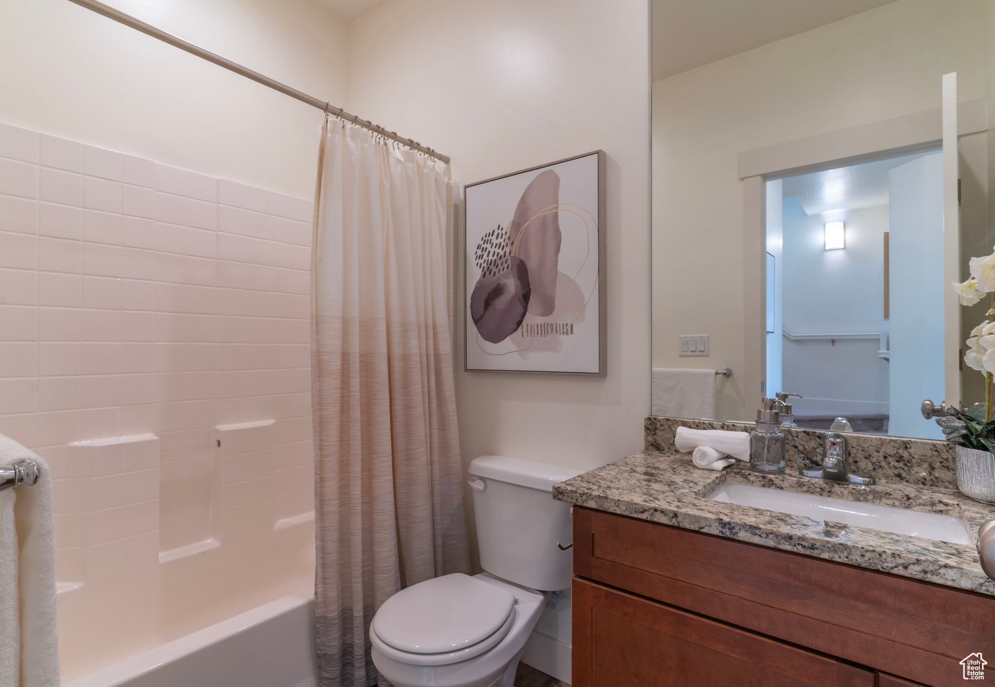 The hallway bathroom just outside the secondary bedrooms features a tub/shower, toilet, sink, oversized mirror and matching granite countertops.