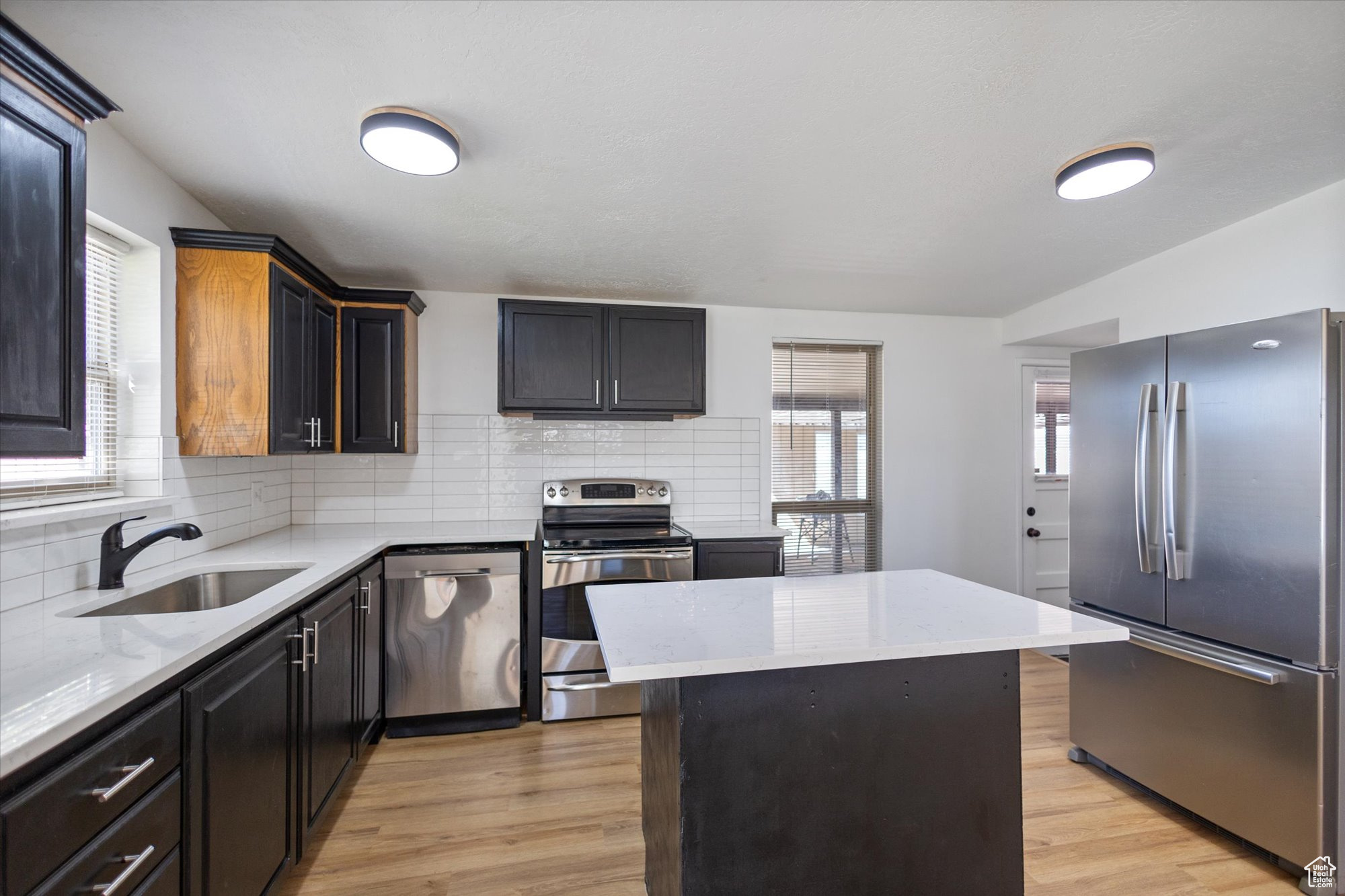 Kitchen featuring stainless steel appliances, light hardwood / wood-style floors, a kitchen island, and sink