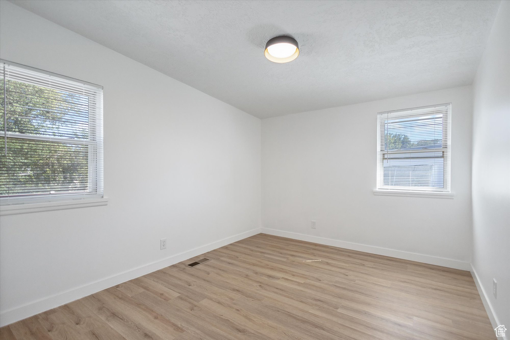 Unfurnished room with a textured ceiling and light hardwood / wood-style floors