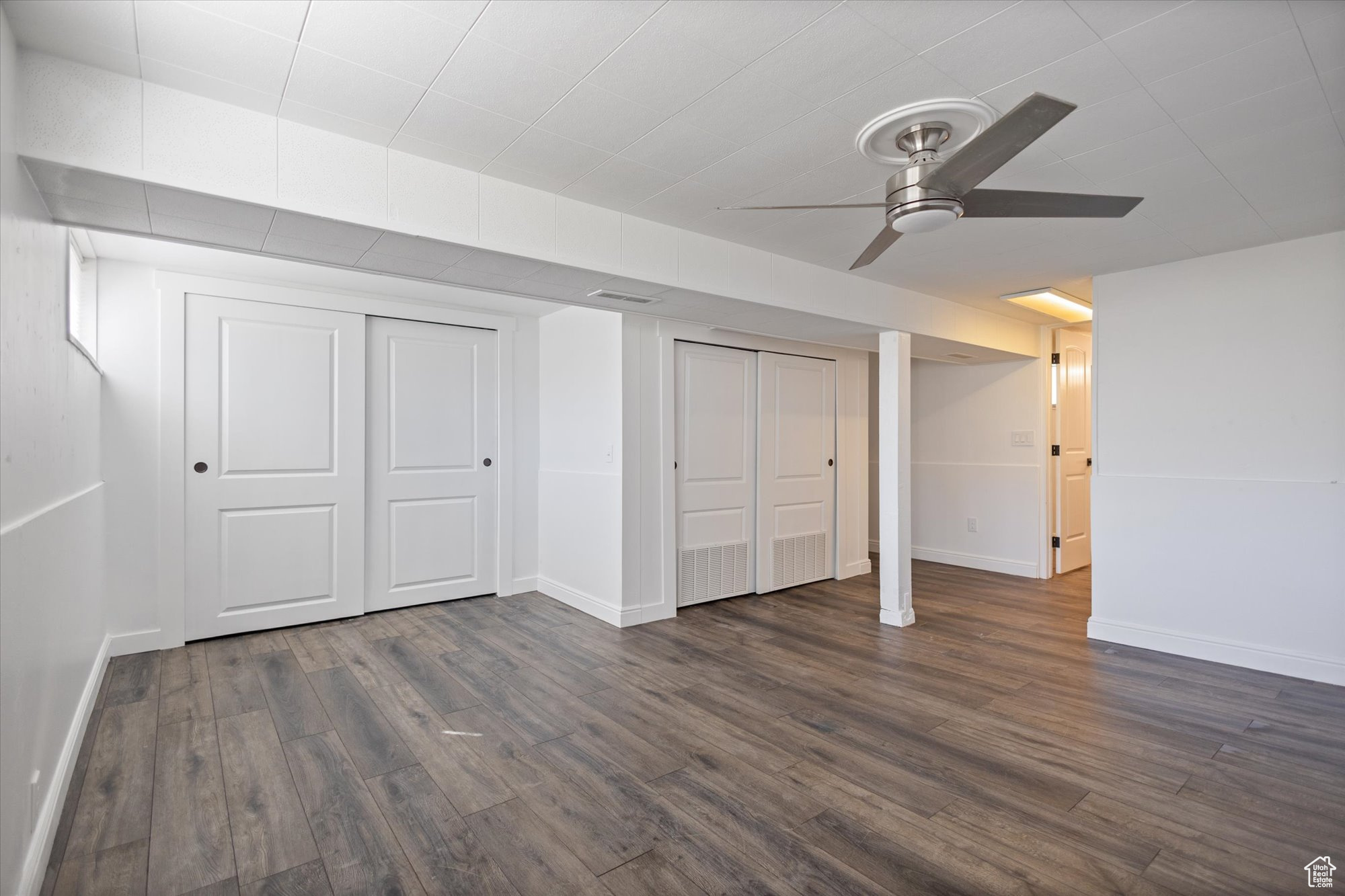 Interior space with multiple closets, ceiling fan, and dark hardwood / wood-style flooring