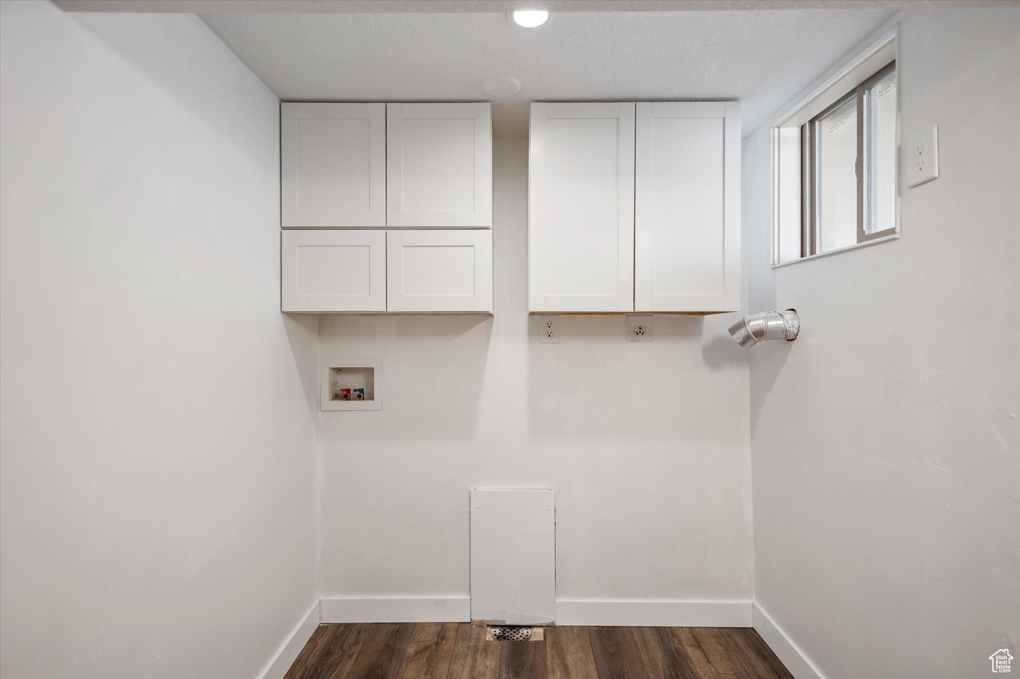 Washroom with washer hookup, dark wood-type flooring, and cabinets