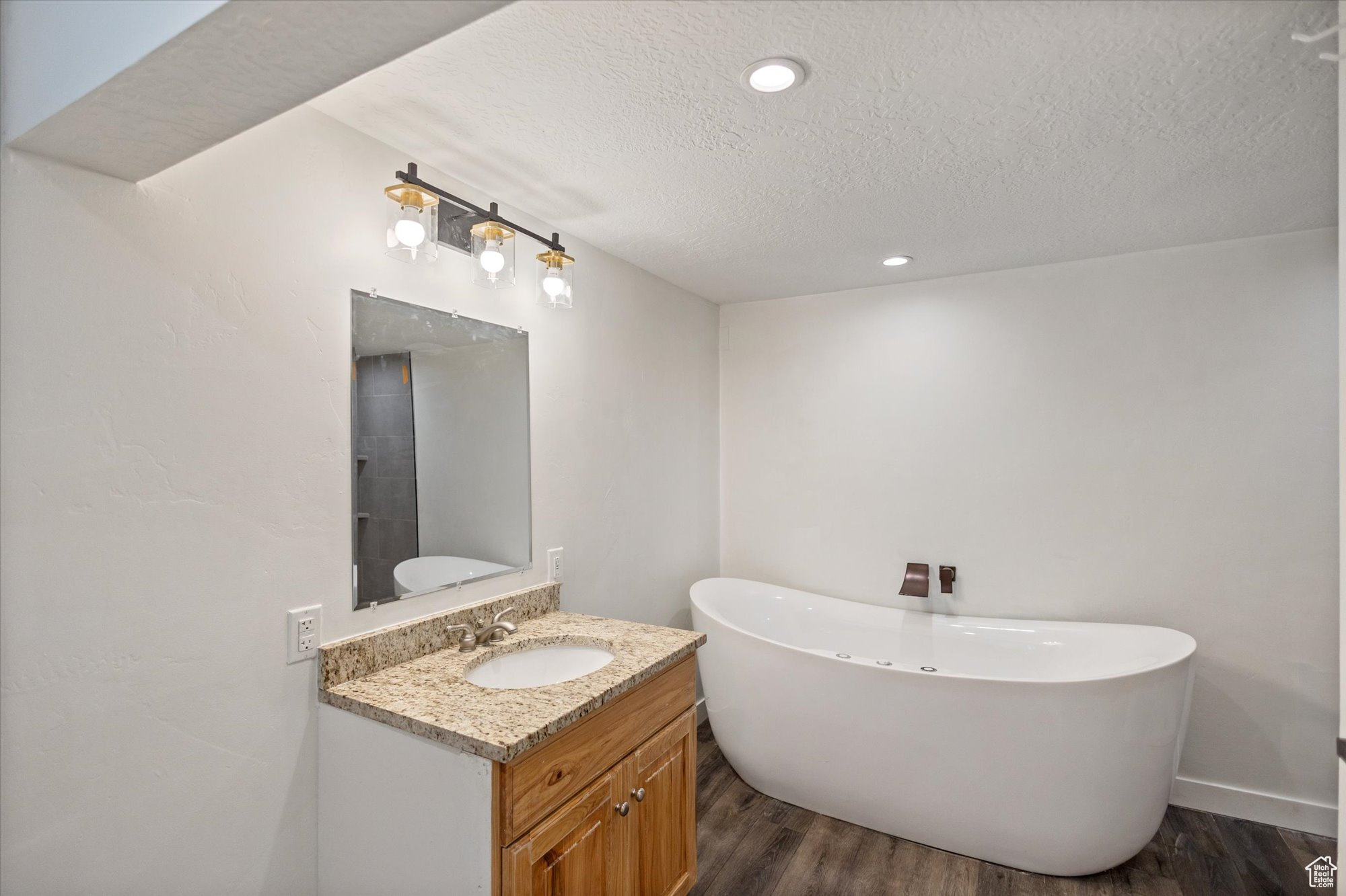 Bathroom with vanity, hardwood / wood-style floors, a textured ceiling, and a tub