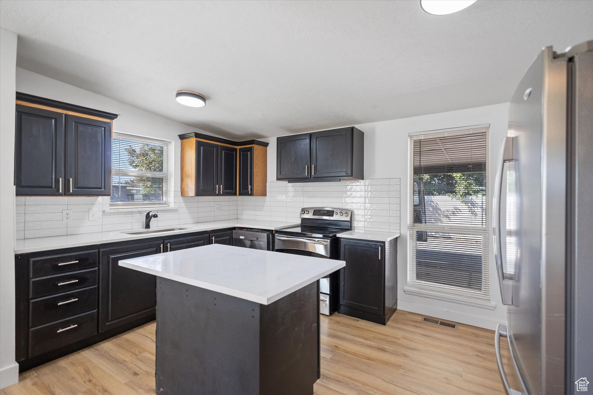 Kitchen featuring light hardwood / wood-style floors, a center island, stainless steel appliances, and a wealth of natural light