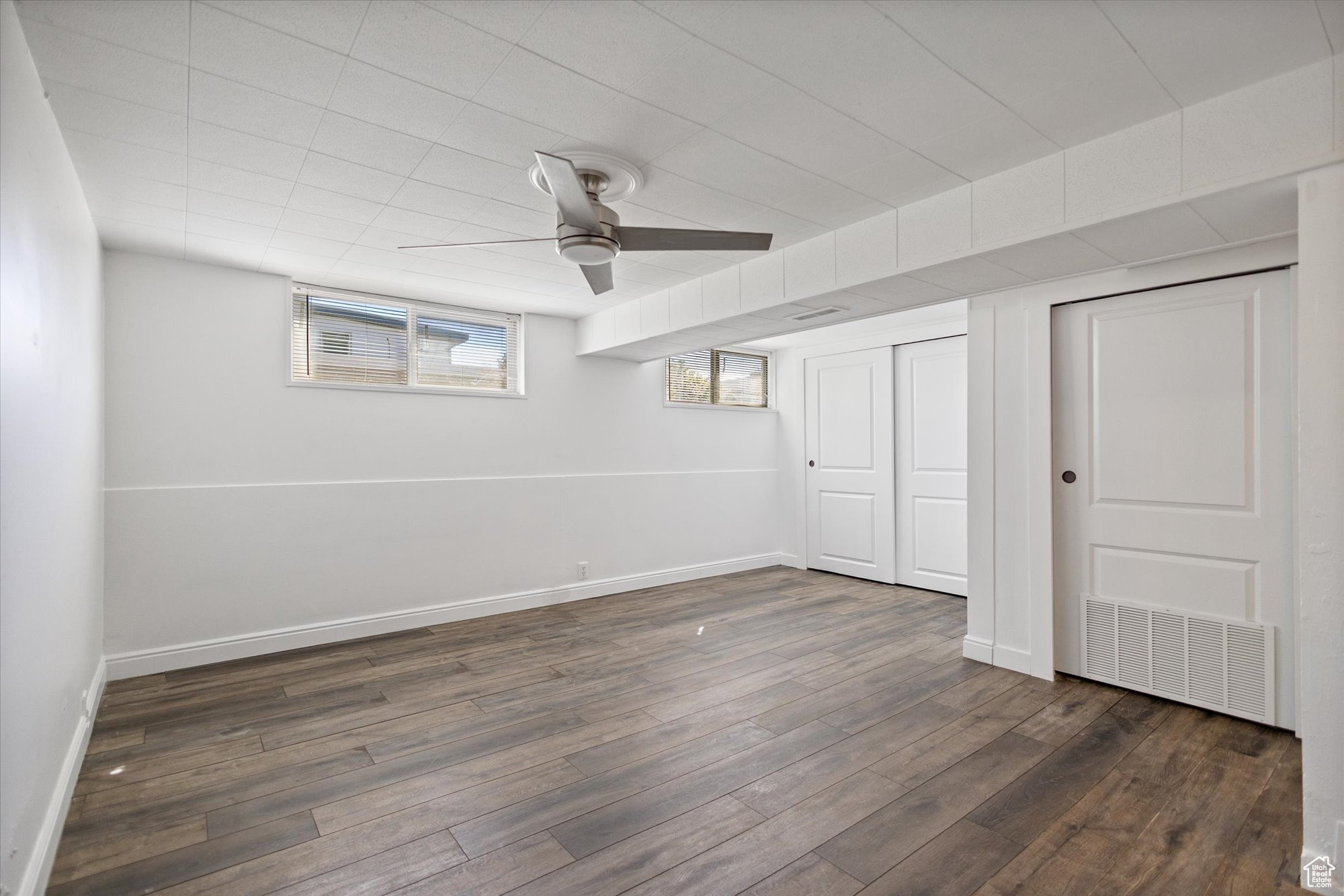 Basement featuring ceiling fan and dark hardwood / wood-style flooring