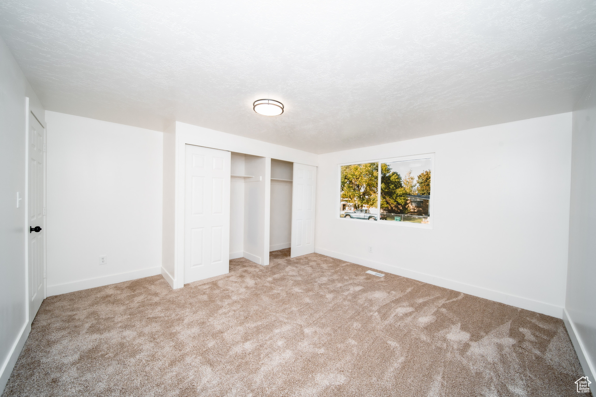 Bedroom with a textured ceiling, light colored carpet, and a closet