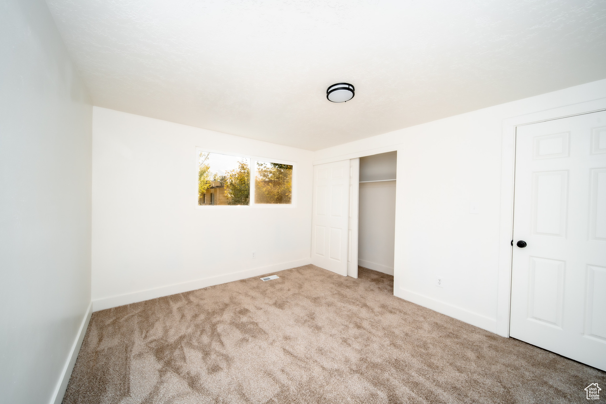 Bedroom with light carpet and a closet