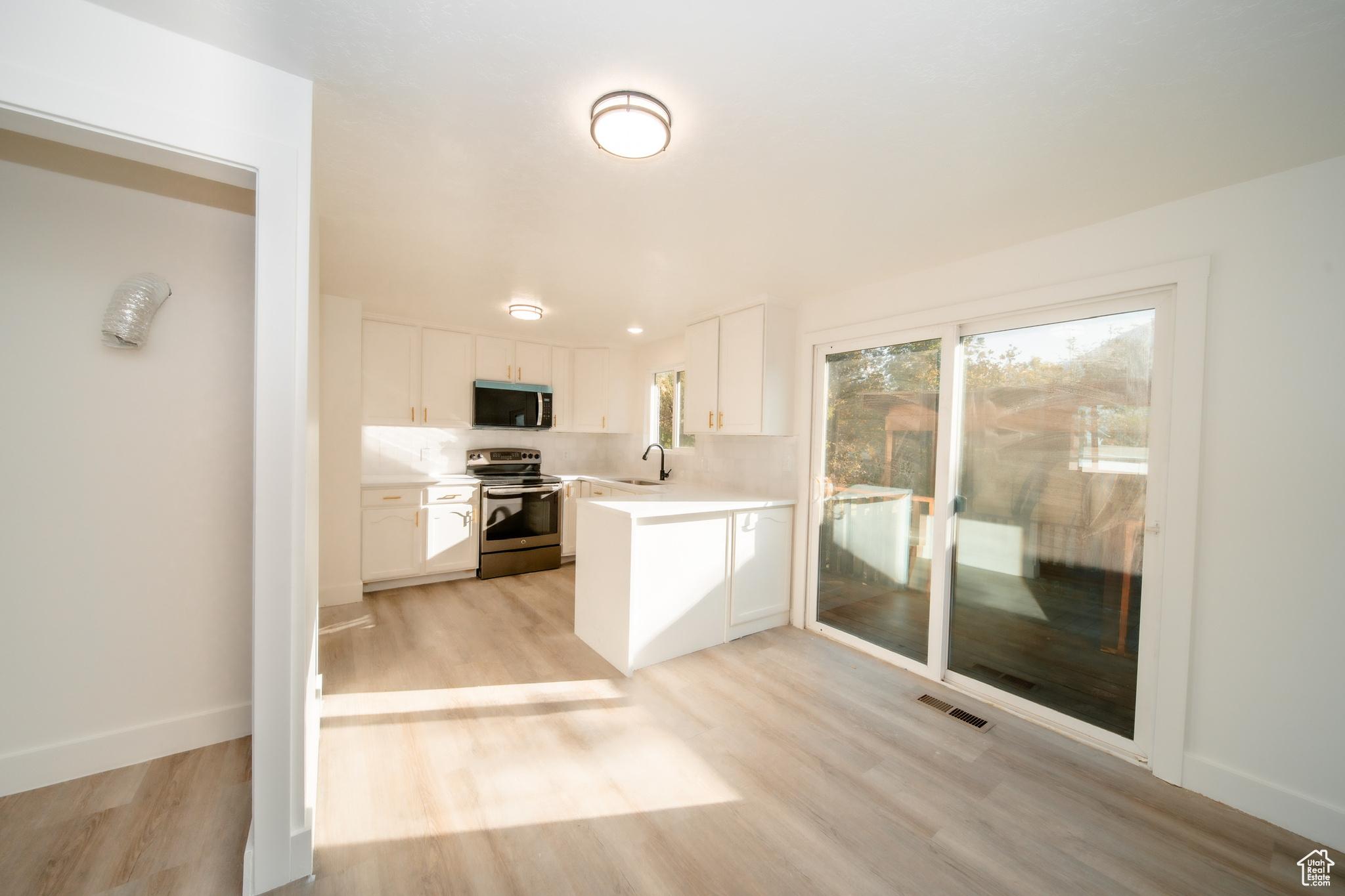 Kitchen featuring stainless steel appliances, white cabinets, light hardwood / wood-style floors, and sink