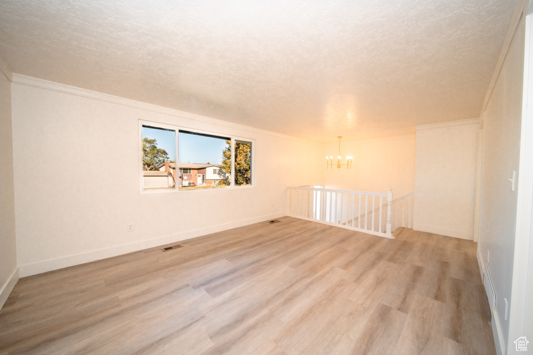 Family room featuring an inviting chandelier, light wood-type flooring, and a textured ceiling