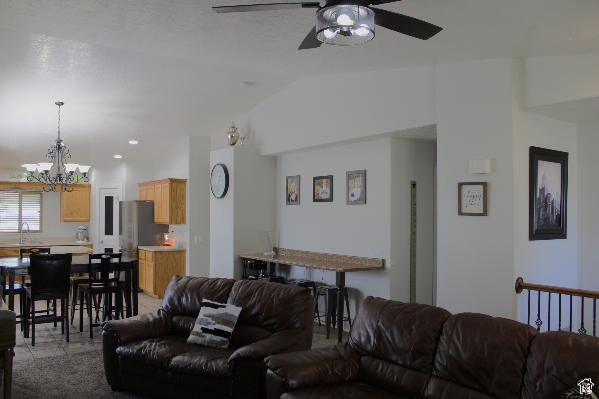 Living room with sink, vaulted ceiling, light colored carpet, and ceiling fan with notable chandelier