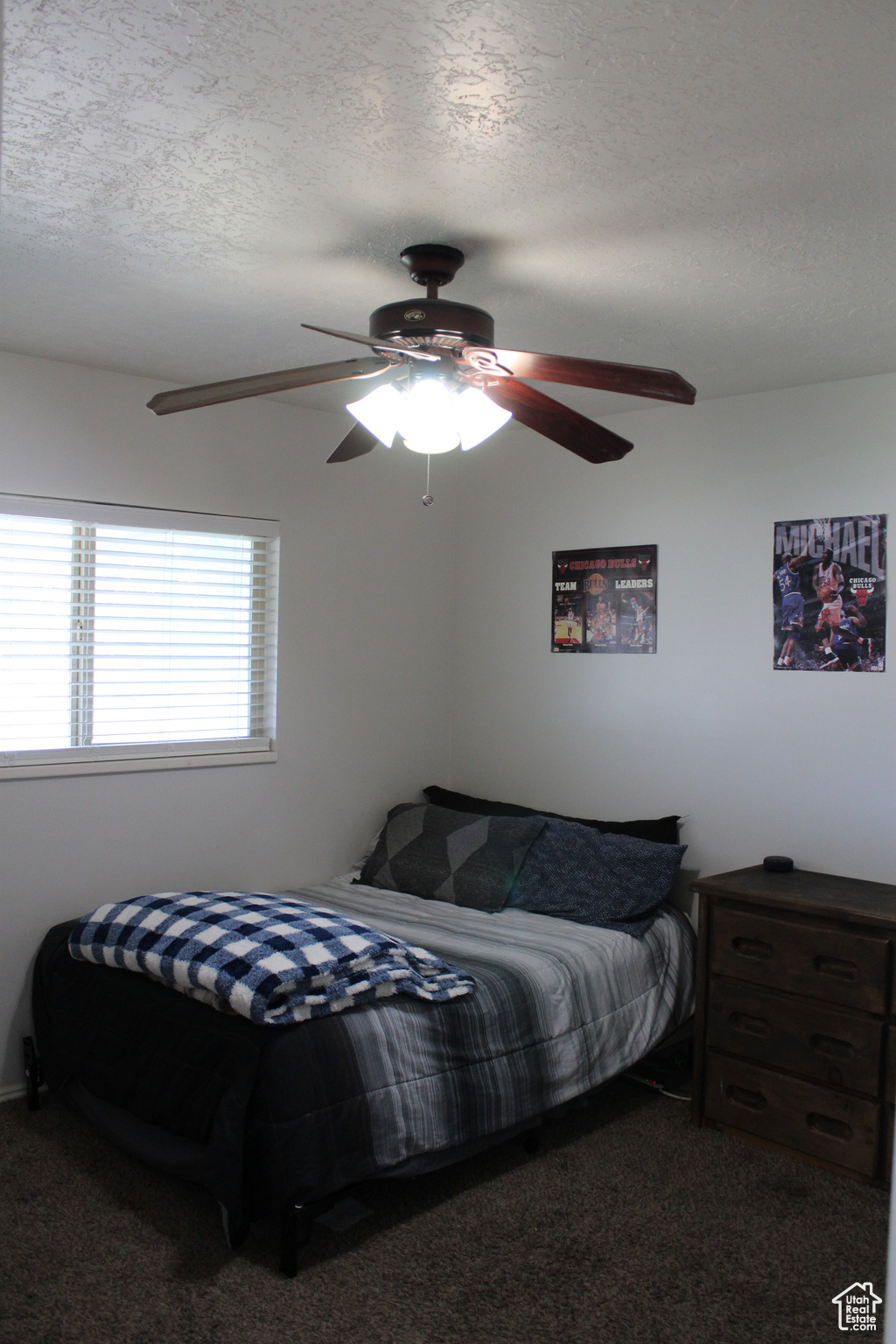 Carpeted bedroom featuring a textured ceiling and ceiling fan