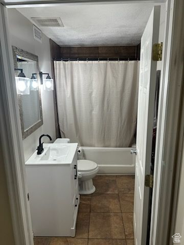 Full bathroom featuring a textured ceiling, toilet, vanity, shower / bathtub combination with curtain, and tile patterned flooring