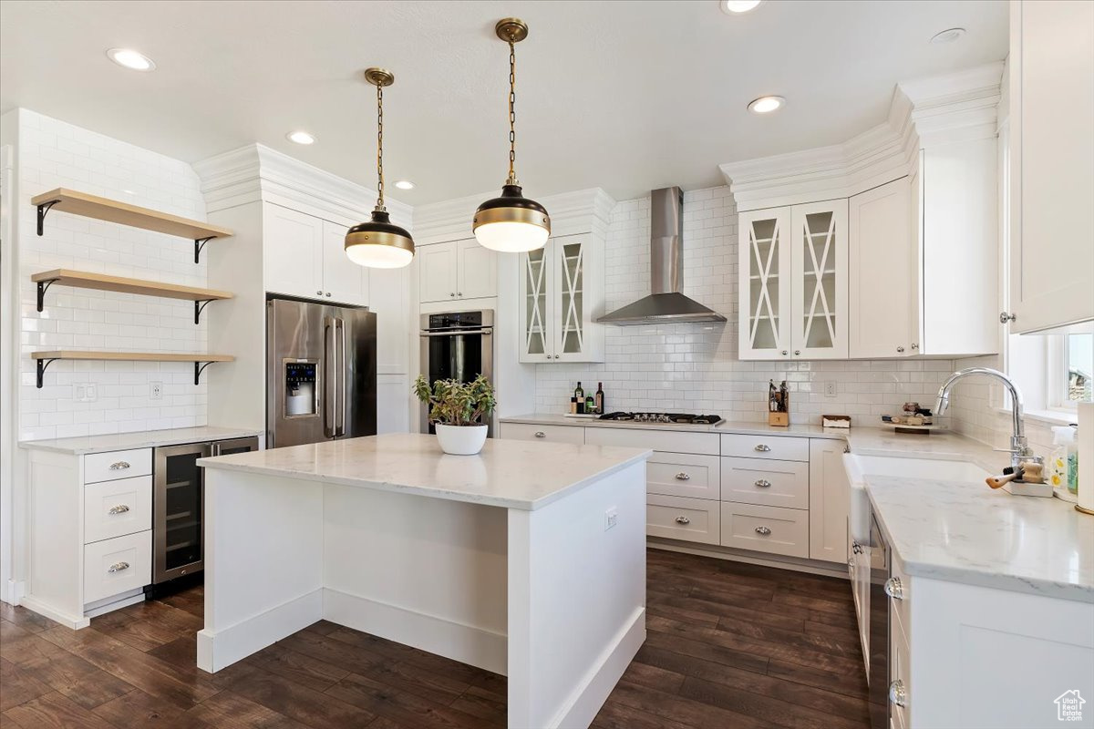 Kitchen with wall chimney exhaust hood, stainless steel appliances, dark hardwood / wood-style flooring, and white cabinetry